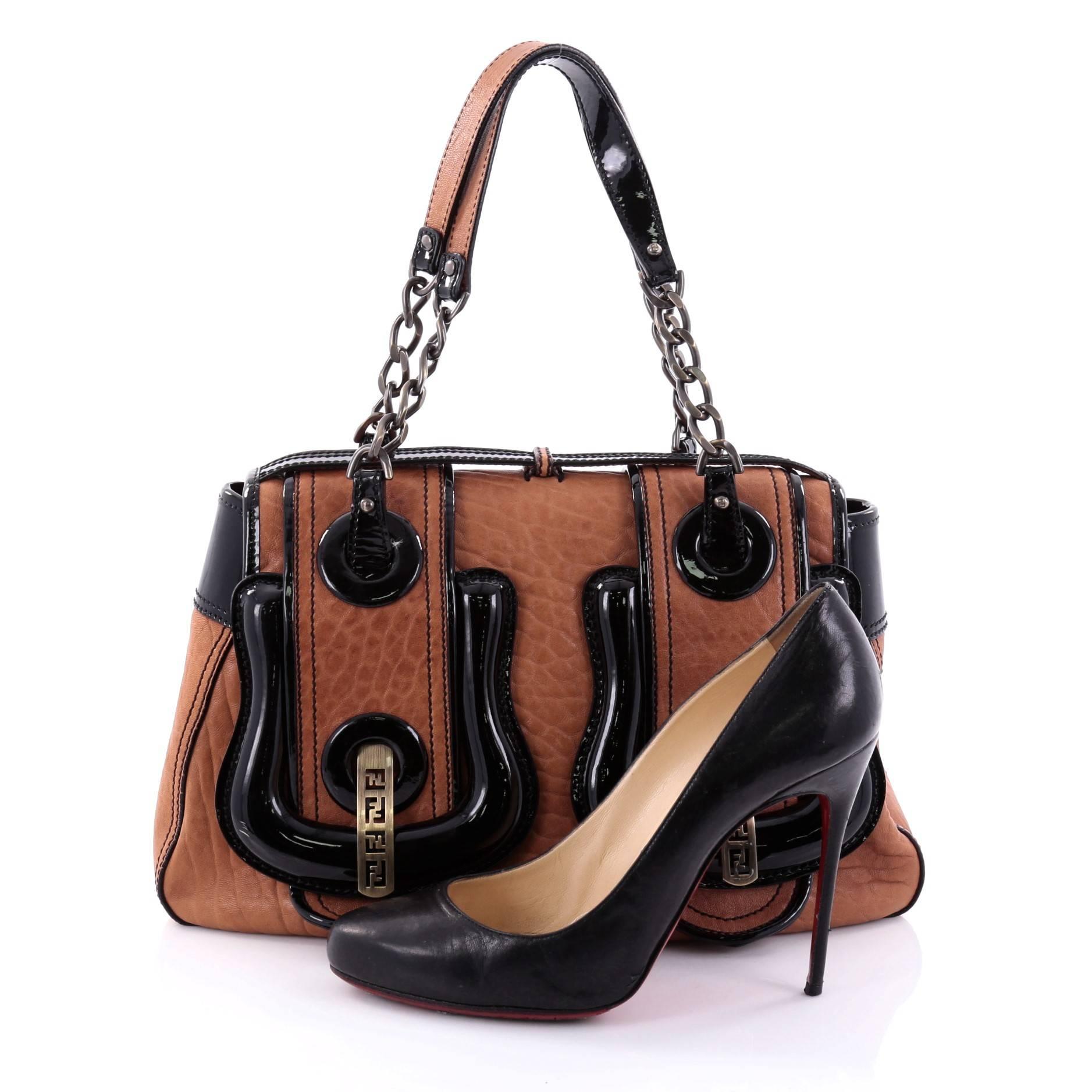 This authentic Fendi B. Bag Leather Medium is a chic bag with a roomy construction that is ideal for work and everyday use. Crafted from light brown leather with black patent leather accents, this bag features oversized buckle details with aged