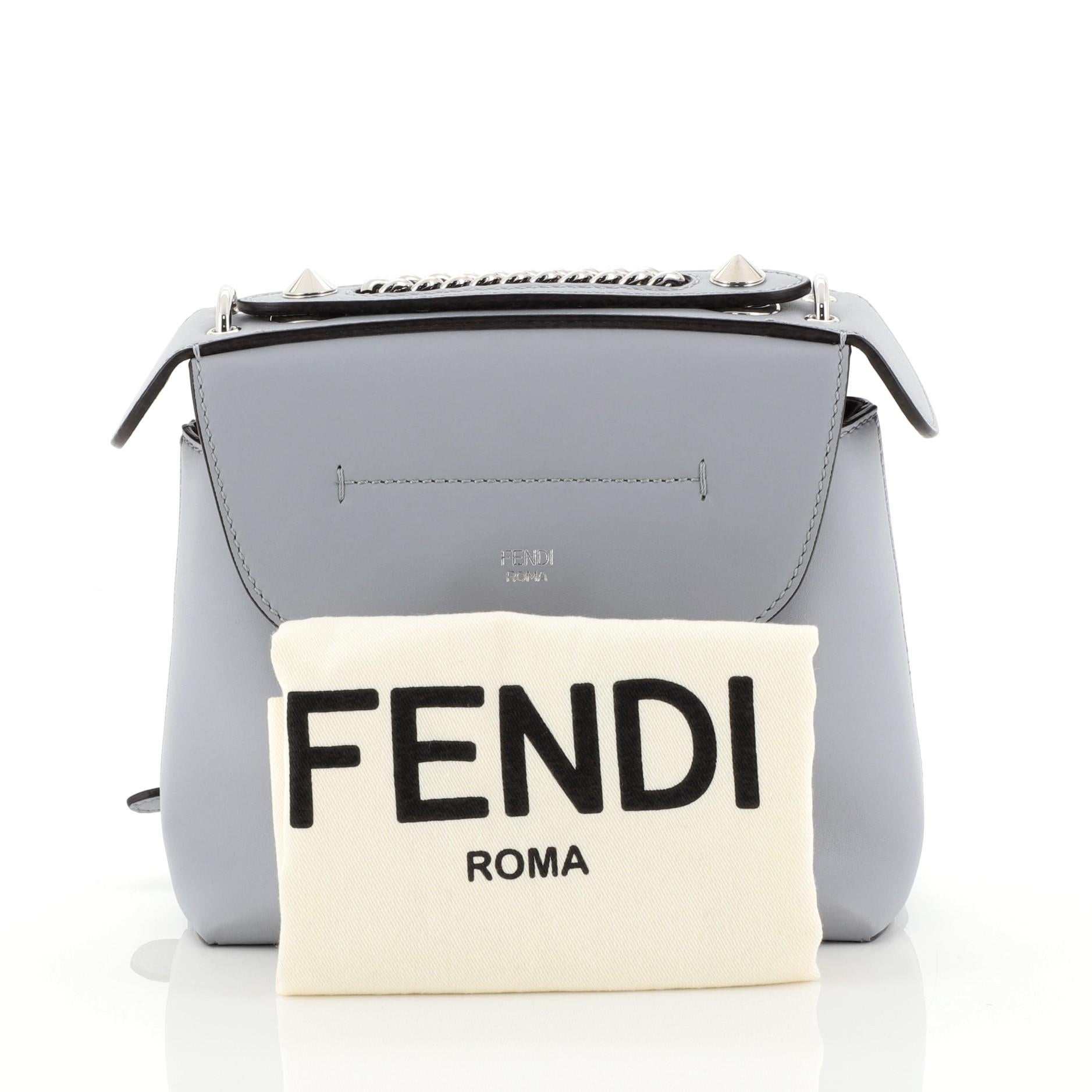 This Fendi Back to School Backpack Leather Mini, crafted in blue leather, features unique studs on the leather top, chain-link straps, front flap with an embossed Fendi signature, and silver-tone hardware. It opens to a black fabric interior with