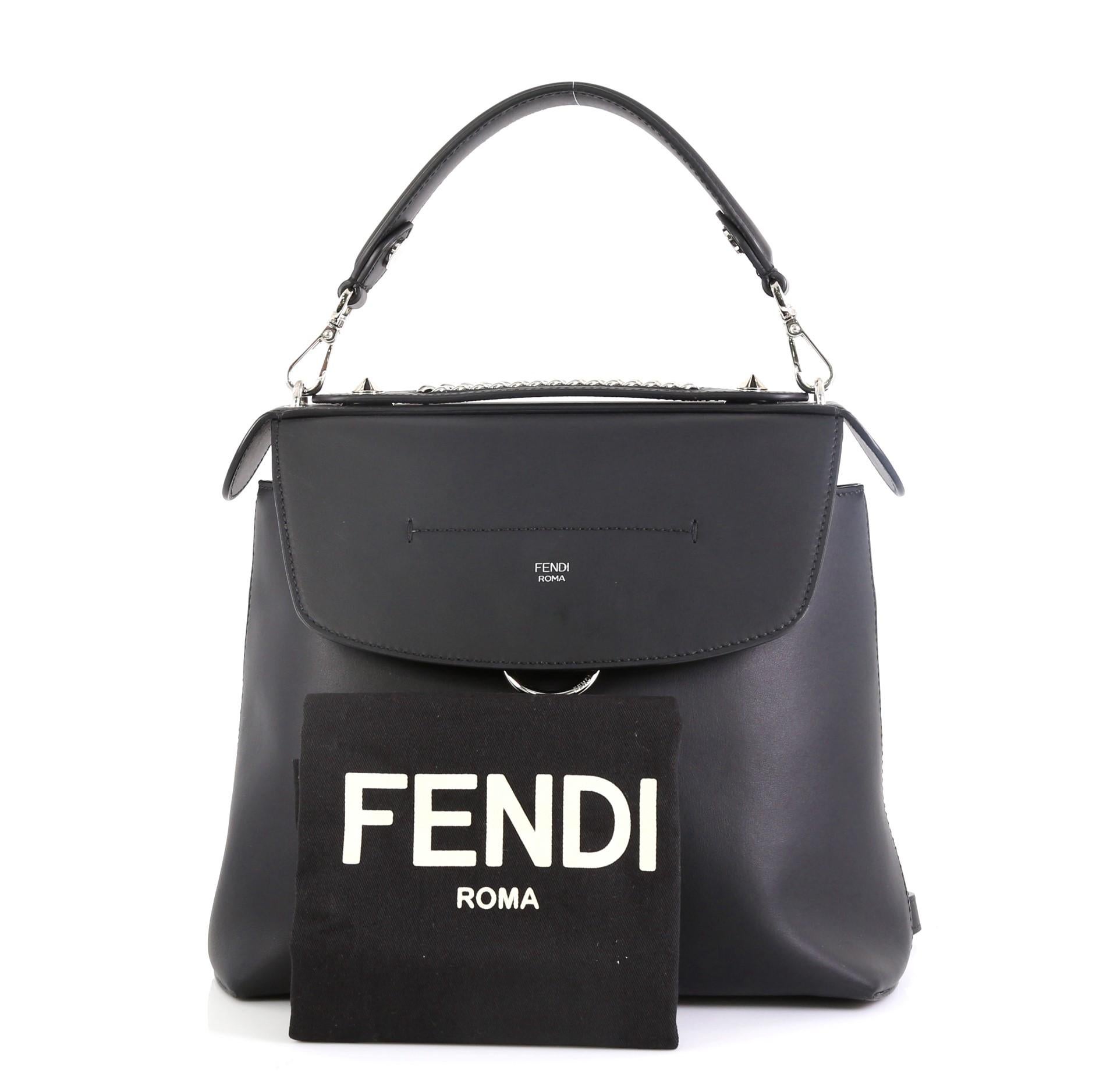 This Fendi Back to School Backpack Leather Small, crafted in black leather, features leather top handle with studs, chain-link straps, front flap with an embossed Fendi signature, and silver-tone hardware. It opens to a black fabric interior with