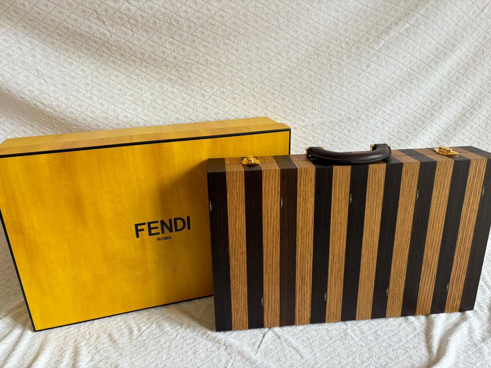 Set da backgammon Fendi Roma con scatola in legno di quercia intarsiata con motivo a strisce di Pequin, impreziosita da un coperchio in plexiglass e manico in pelle di vitello nappa in tinta / Made in Italy
SKU: 7AL000AM4UF1K65 
Cartellini originali