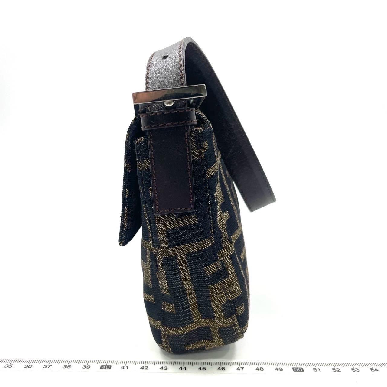 Die Fendi Baguette, eine klassische Ikone mit dem beliebten Zucca-Print, wird vorgestellt. Diese braune Umhängetasche im Vintage-Stil ist ein Muss für Modefans, denn sie vereint Stil und Funktionalität. Der Inbegriff von zeitloser Eleganz für Ihre