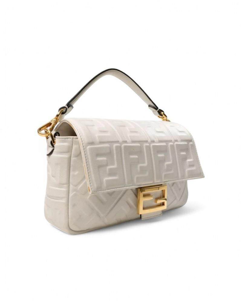 Borsa firmata Fendi, linea Embossed, modello Baguette nella misura medium, realizzata in pelle bianca con iconico motivo FF a rilievo dall’effetto tridimensionale. Dotata di una patta con classico logo del brand “FF” in metallo e chiusura a bottone