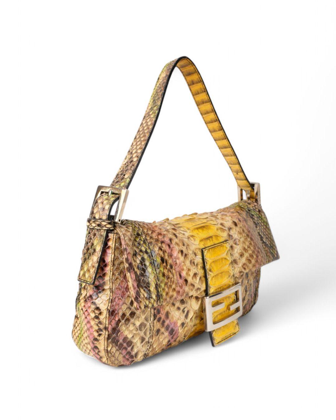 Bolso Baguette de Fendi en tamaño MM, realizado en piel de pitón multicolor con tonos amarillos y herrajes plateados. Presenta una solapa frontal con el clásico logotipo metálico de la marca 
