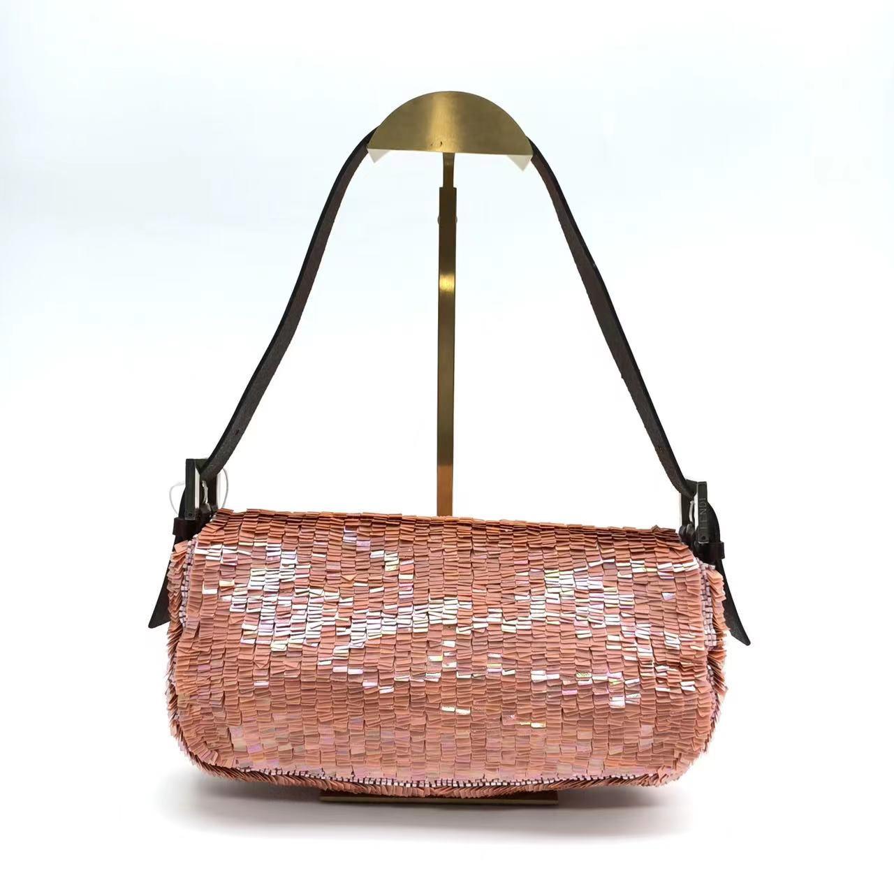 This vintage Fendi Baguette is the perfect accessory to make a statement. Covered with pink mauve sequins and a luxurious green silk lining, this handbag has a brown leather strap and buckle. All the colors compliment each other, making it a