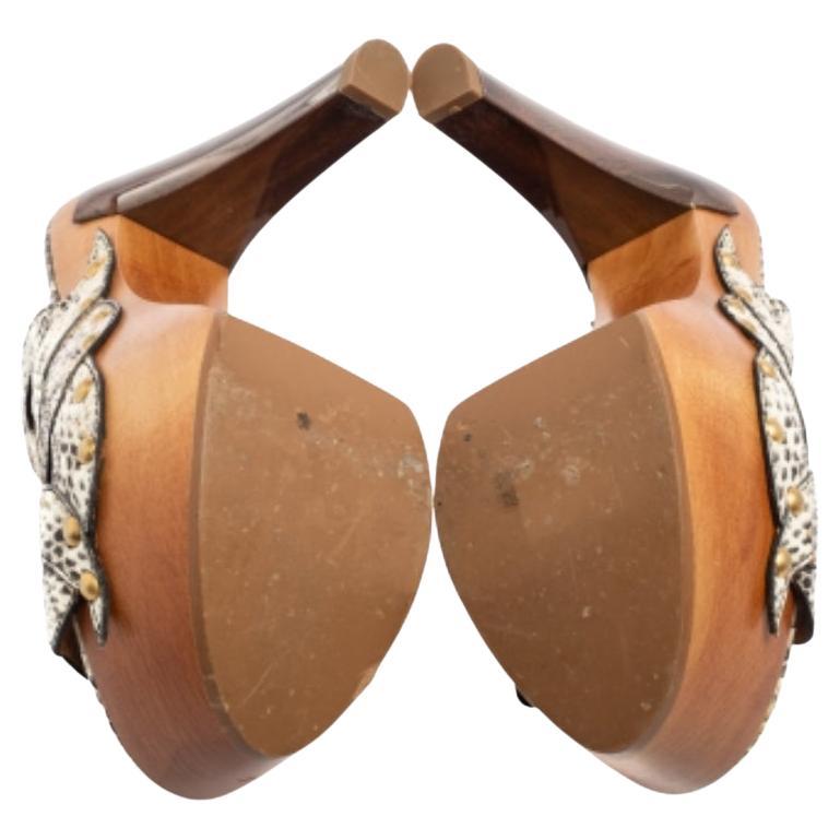 Das Haus Fendi entwirft Designs, die immer beeindruckend und trendy sind. Diese Slide-Sandalen von Fendi sind ein echter Klassiker, der Sie schick aussehen lässt! Sie sind aus beige-braunem Pythonleder gefertigt und zeichnen sich durch goldfarbene