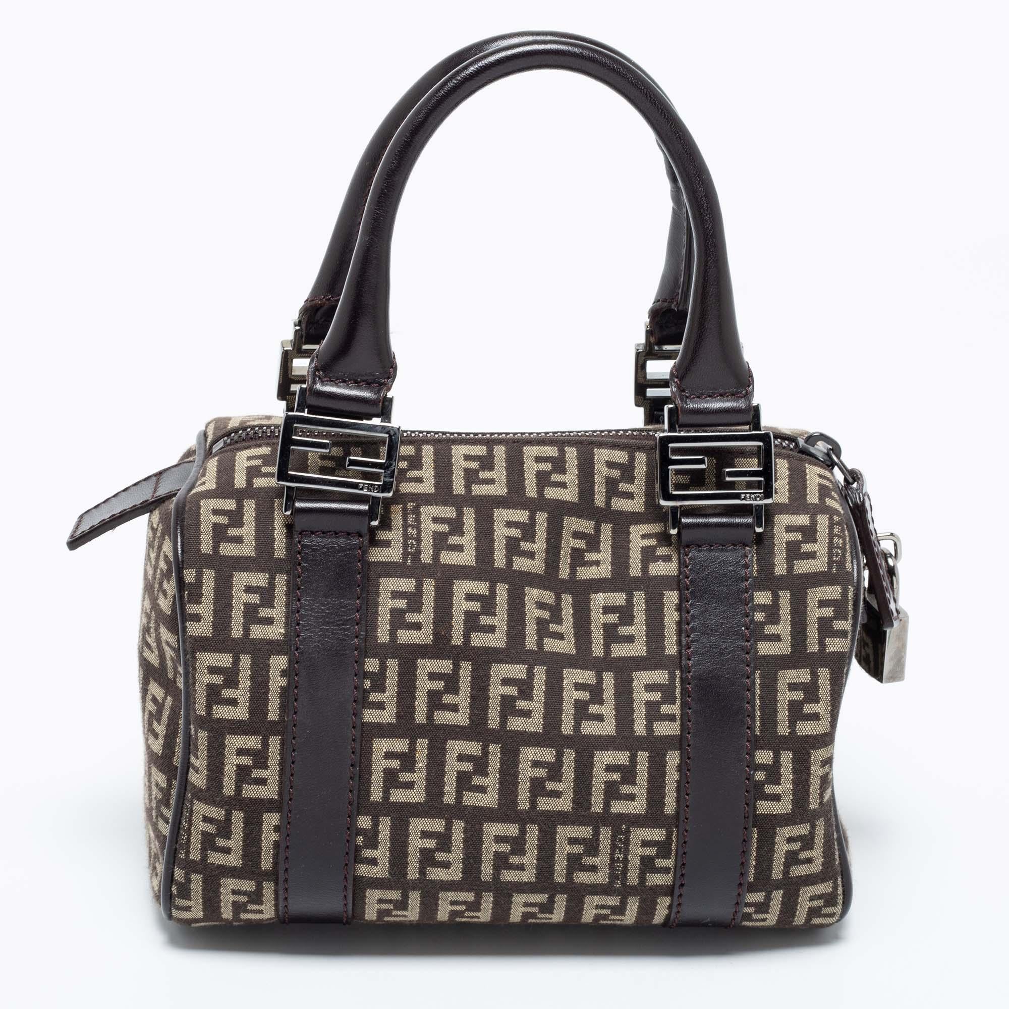  This elegant Forever Bauletto bag from Fendi is crafted from canvas and leather and is perfect for your fashionable outings. The beautiful bag features splendid details in the form of dual top handles and a padlock. The top zip closure opens to a
