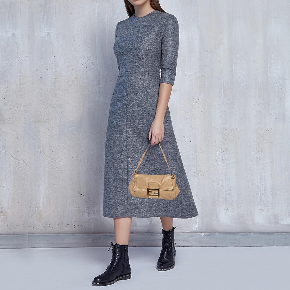 The Baguette was created by Silvia Venturi Fendi in 1997, and it was an instant rage! Made from leather in a beige hue, it has the FF logo on the flap that opens to a well-sized canvas-lined interior for your essentials. The bag suspends from a