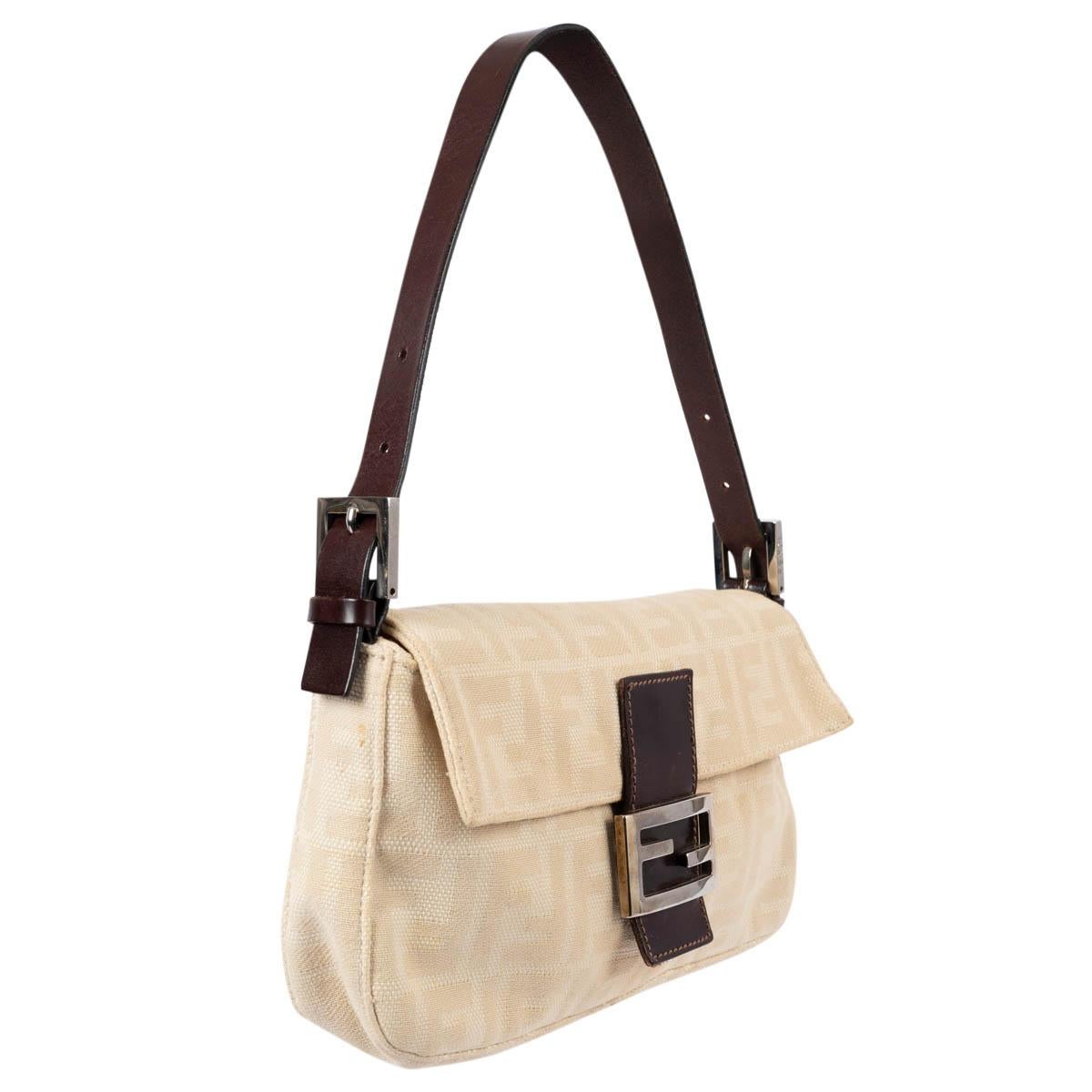 100% authentic Fendi baguette bag in beige Zucca canvas with dark brown leather trim and silver-tone metal buckle. Lined in dark brown nylon with one zipper pocket against the back. Has been carried and shows some darkening to the canvas, scratches