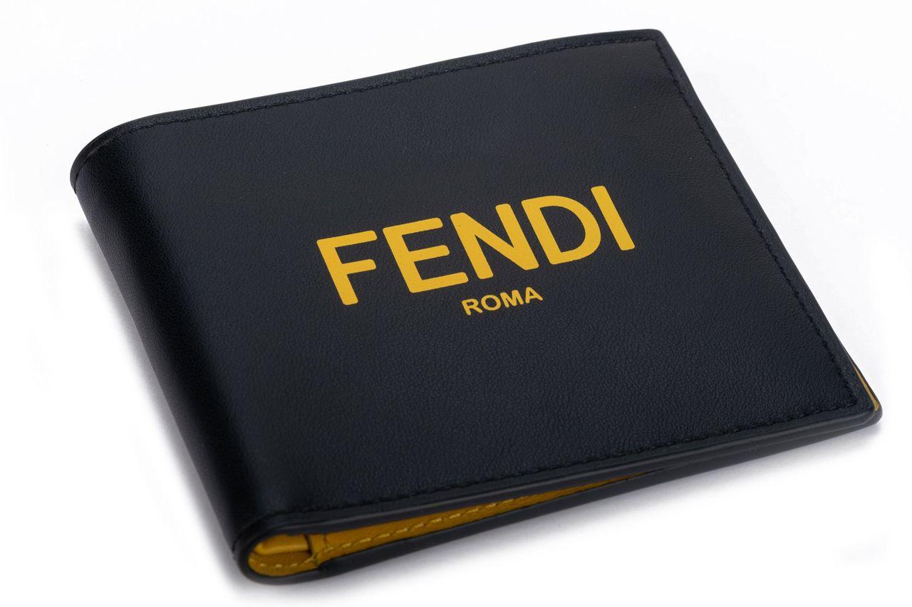 Fendi fold wallet in black and yellow. The briefcase is crafted of leather the outside is kept in black with Fendi written in yellow on it. The interior is yellow leather with multiple card departments and one big department for cash. The piece is