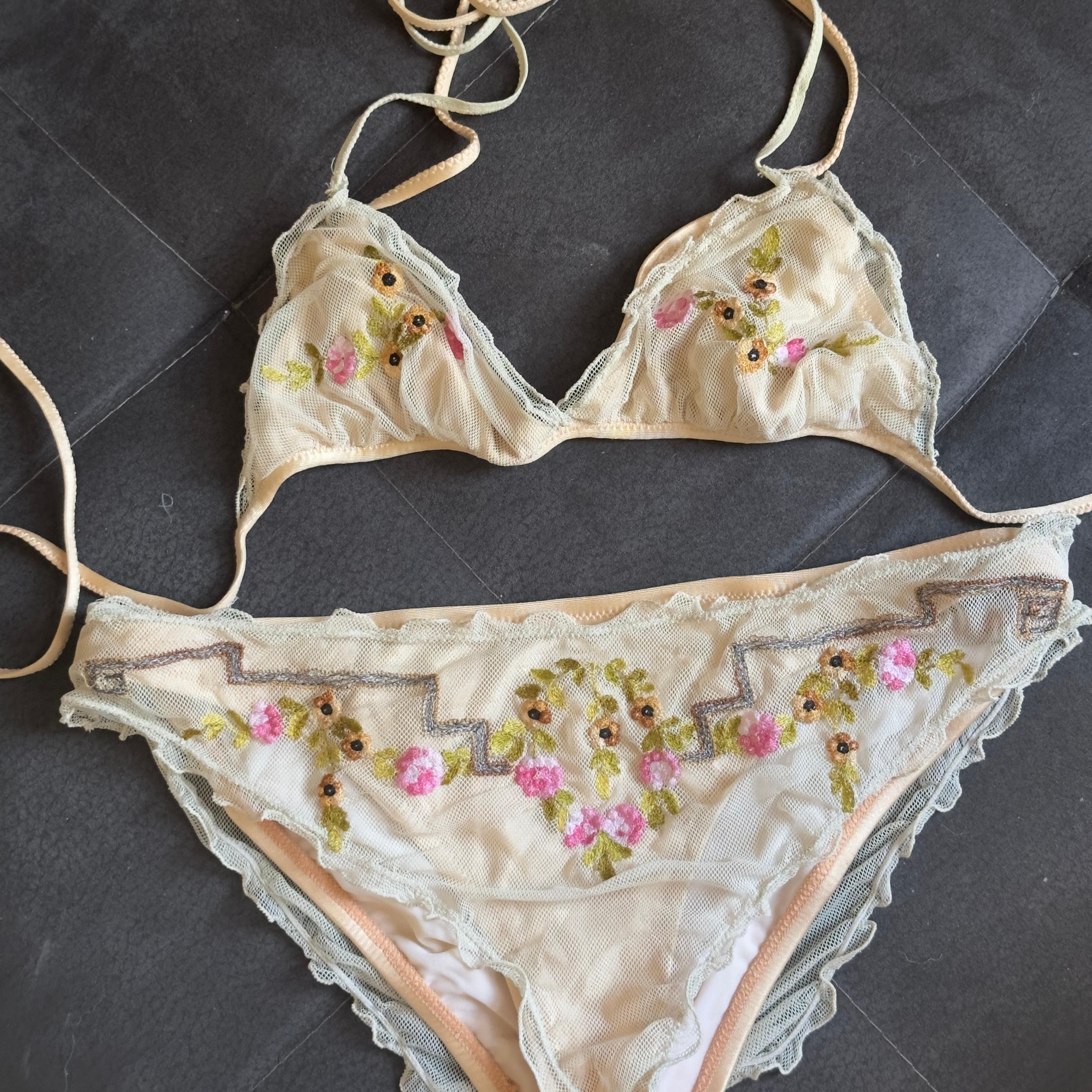 Un verdadero tesoro de colección de Fendi.
Este bikini data de la década de 2000 y forma parte de la línea más atrevida y refinada de la Maison. Confeccionado en tul transparente de color nude, está adornado con bordados florales en tonos pastel y