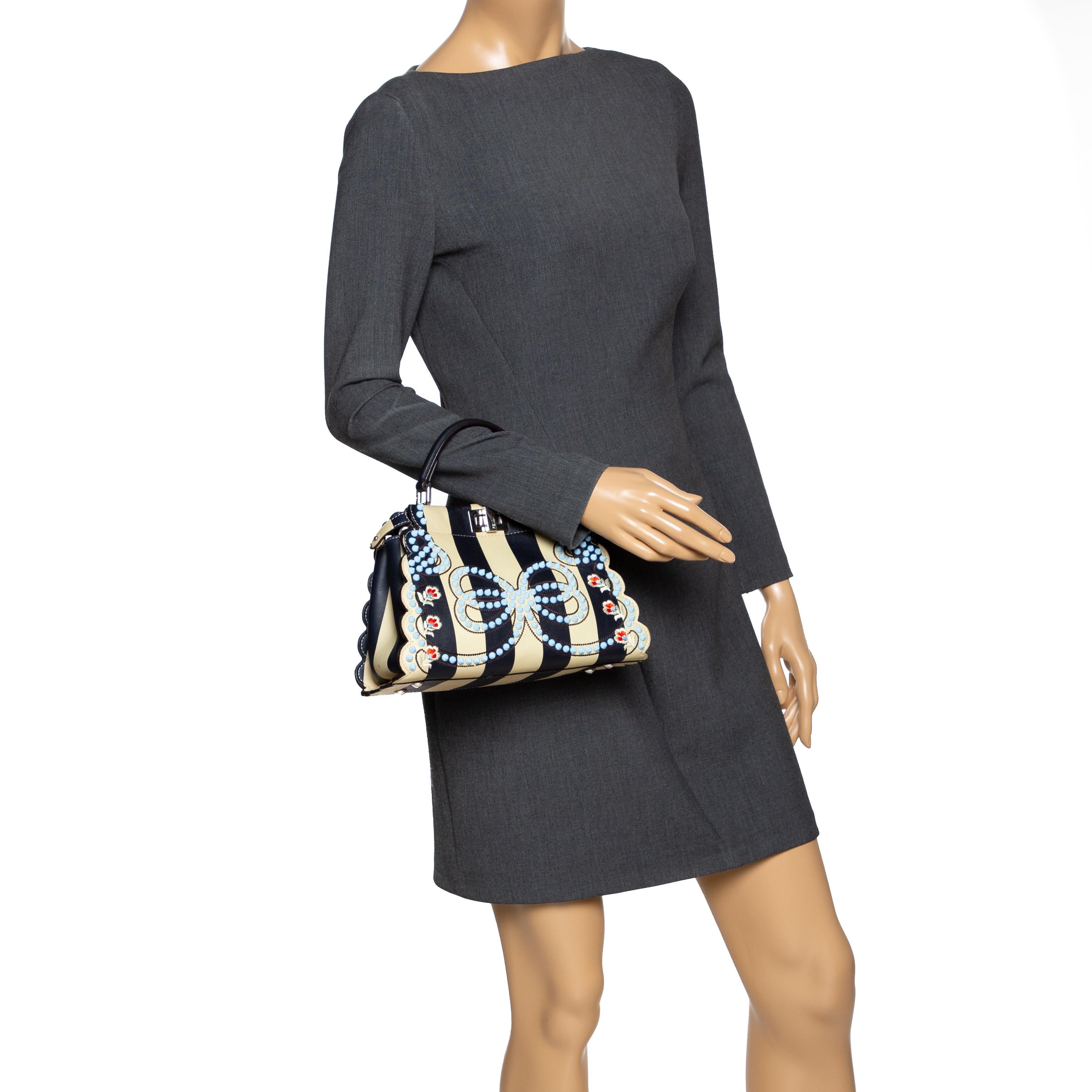 This exquisite Peekaboo from Fendi is highly coveted, and since its birth in 2009, it has swayed us with its shape, design, and beauty. This black & beige version comes meticulously crafted from leather and designed with a top handle for you to