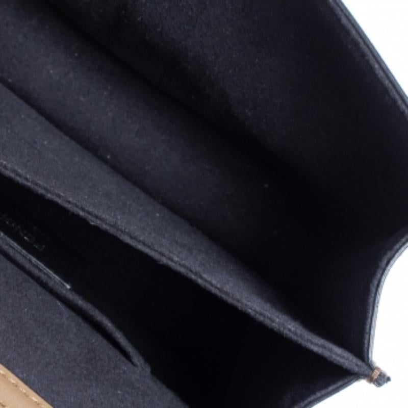 This Kan I F Fendi bag exudes an aura of excellence and an unequaled standard of craftsmanship. It has been crafted from leather and velvet exhibiting the signature Zucca pattern in a black and brown shade and styled with pyramid studs. It opens to