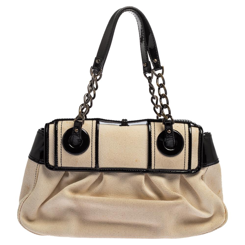 Fall in love instantly with this gorgeous B bag by Fendi. Made from back/ivory canvas and patent leather, this piece will smoothly last you season after season. It has two chain-leather handles, large buckle details on the front, and a well-sized