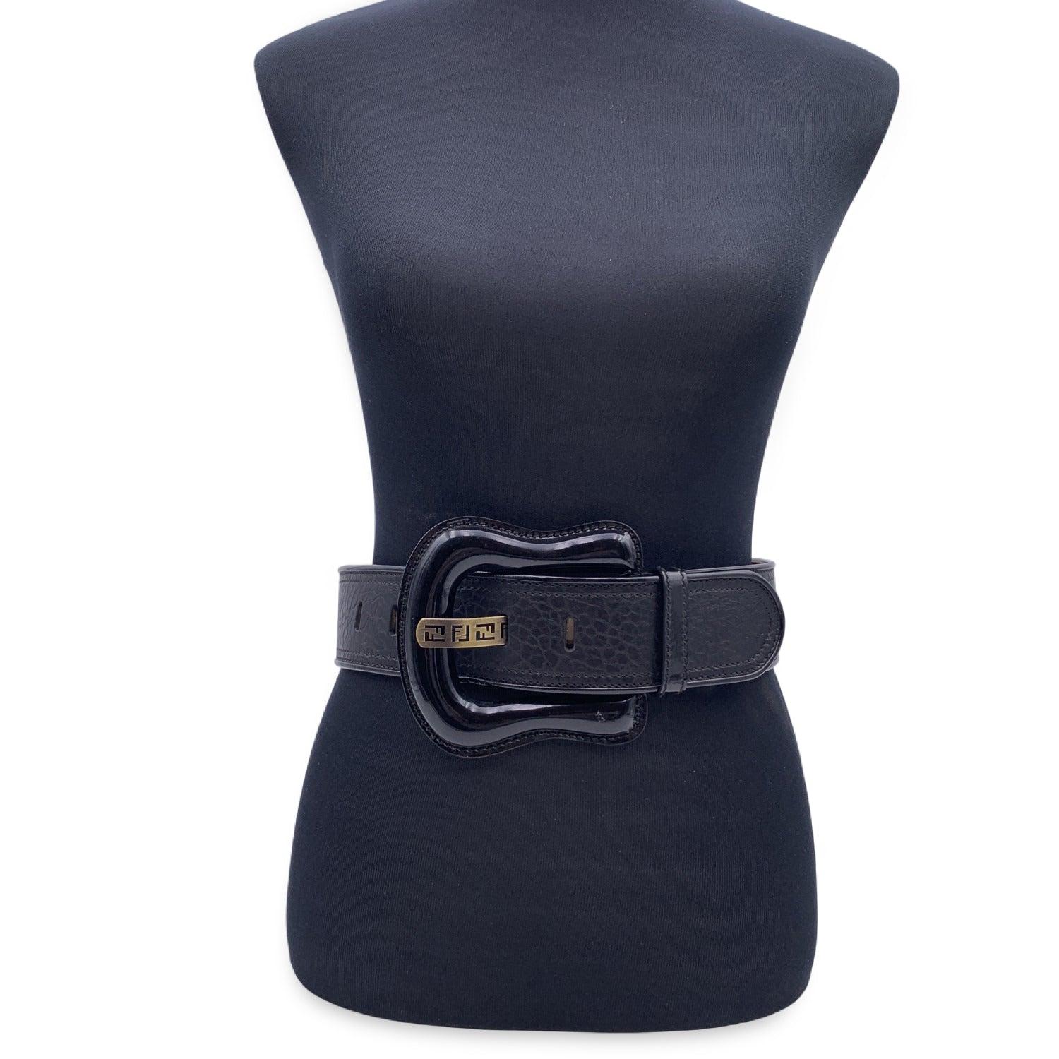 Fendi B Buckle Wide Belt. Black leather and black patent leather oversized buckle with logo-cutouts on the pin. Width: 2.25 inches - 5.6 cm. 'FENDI' engraved on the reverse of the buckle. 5 holes adjustament. Total length (Only leather): 34 inches -