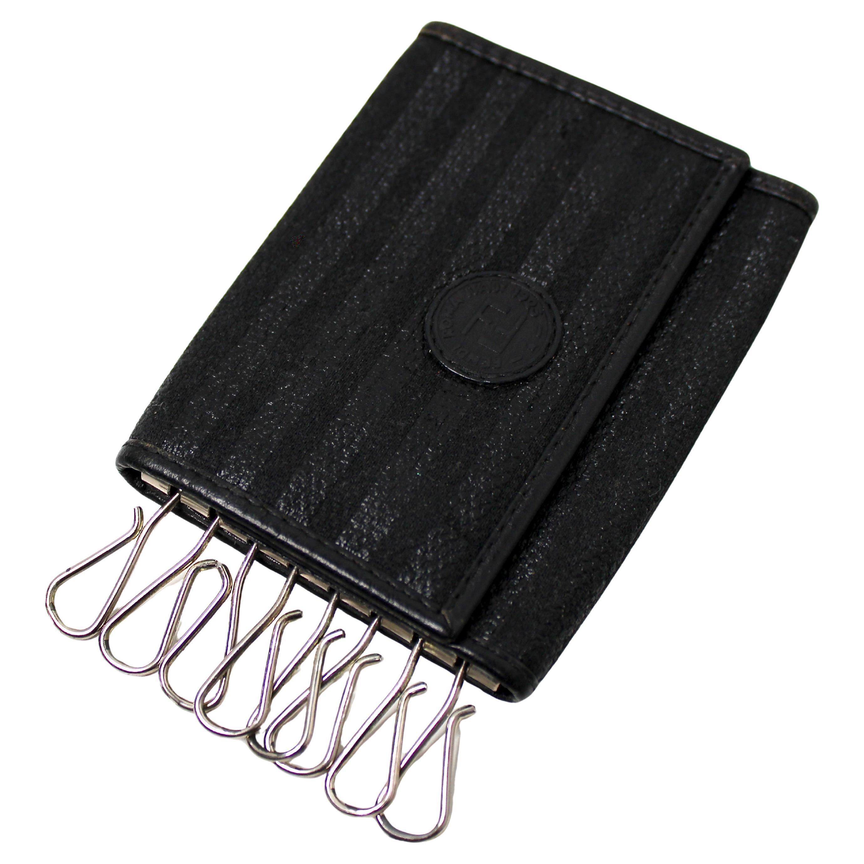 La custodia per 8 tasti Fendi in pelle nera e tela rivestita è un accessorio sofisticato e pratico, progettato per l'individuo moderno che apprezza sia lo stile che la funzionalità. Realizzato in pelle nera di alta qualità abbinata a una resistente