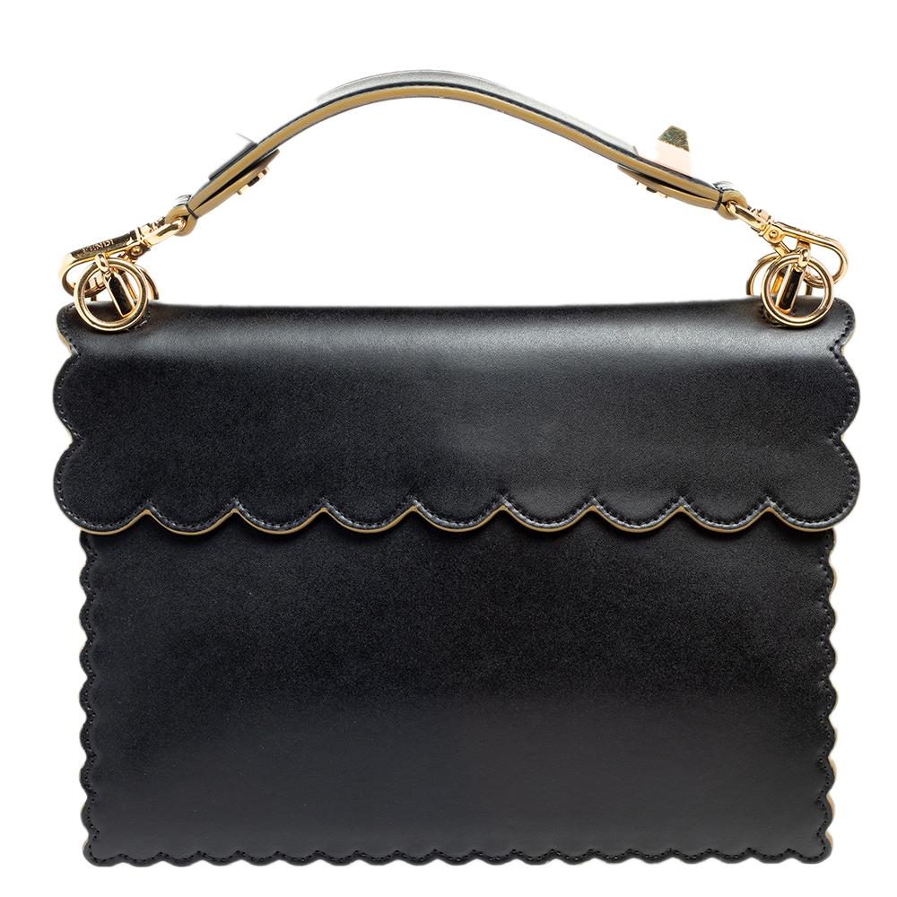 This Kan I Fendi bag exudes an aura of excellence and an unequaled standard of craftsmanship. It has been crafted from leather in a black shade and styled with pyramid studs and scalloped edges. It opens to a spacious suede-lined interior that can
