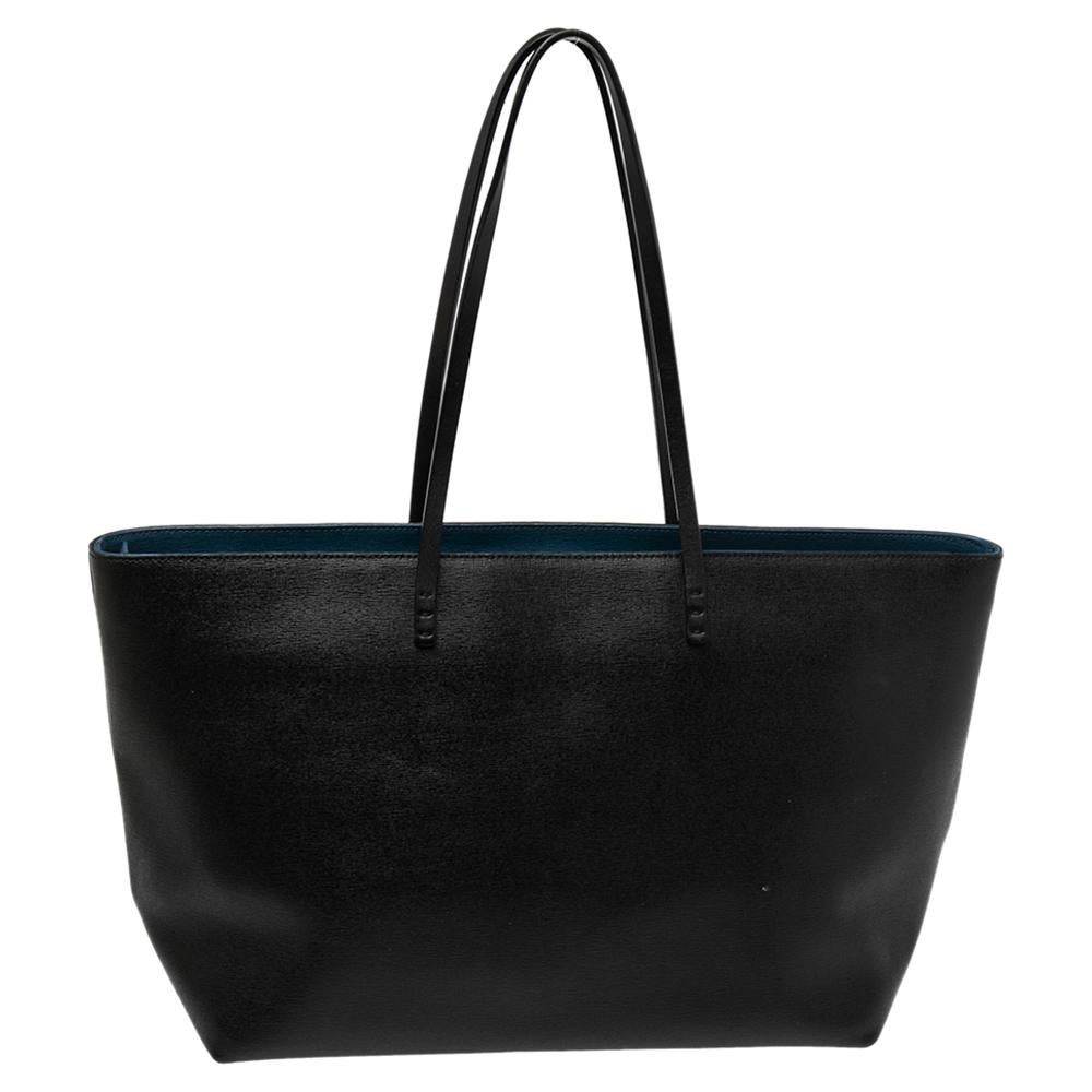 Functional and stylish, this tote is from Fendi! It has been crafted from leather and designed in a black shade featuring monster eyes and a zipper on the front. The bag is held by two handles and is equipped with a spacious fabric interior capable