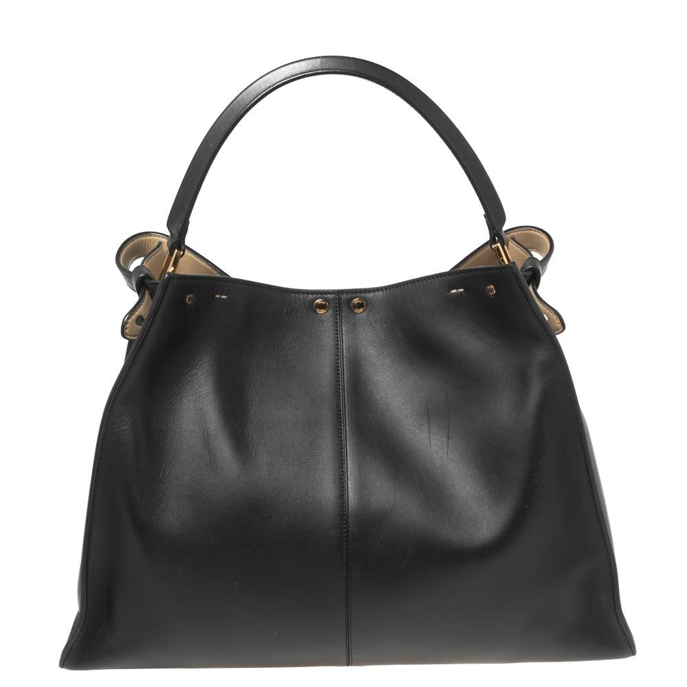 This exquisite Peekaboo X-Lite bag from Fendi is a grand update of an iconic design. This version comes meticulously crafted from black leather and is designed with a top handle for you to swing in your hand or in the crook of your arm. A twist-lock