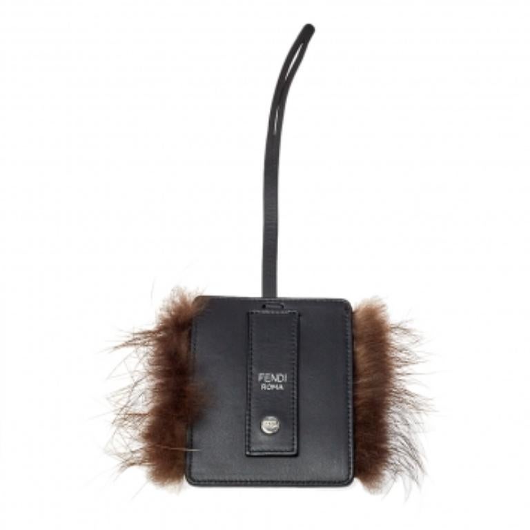 Adorable and playful, this luggage charm by Fendi features a small black leather silhouette featuring the signature Monster eye detail with studs. The charm is held by a leather strap and can be attached to your luggage easily.