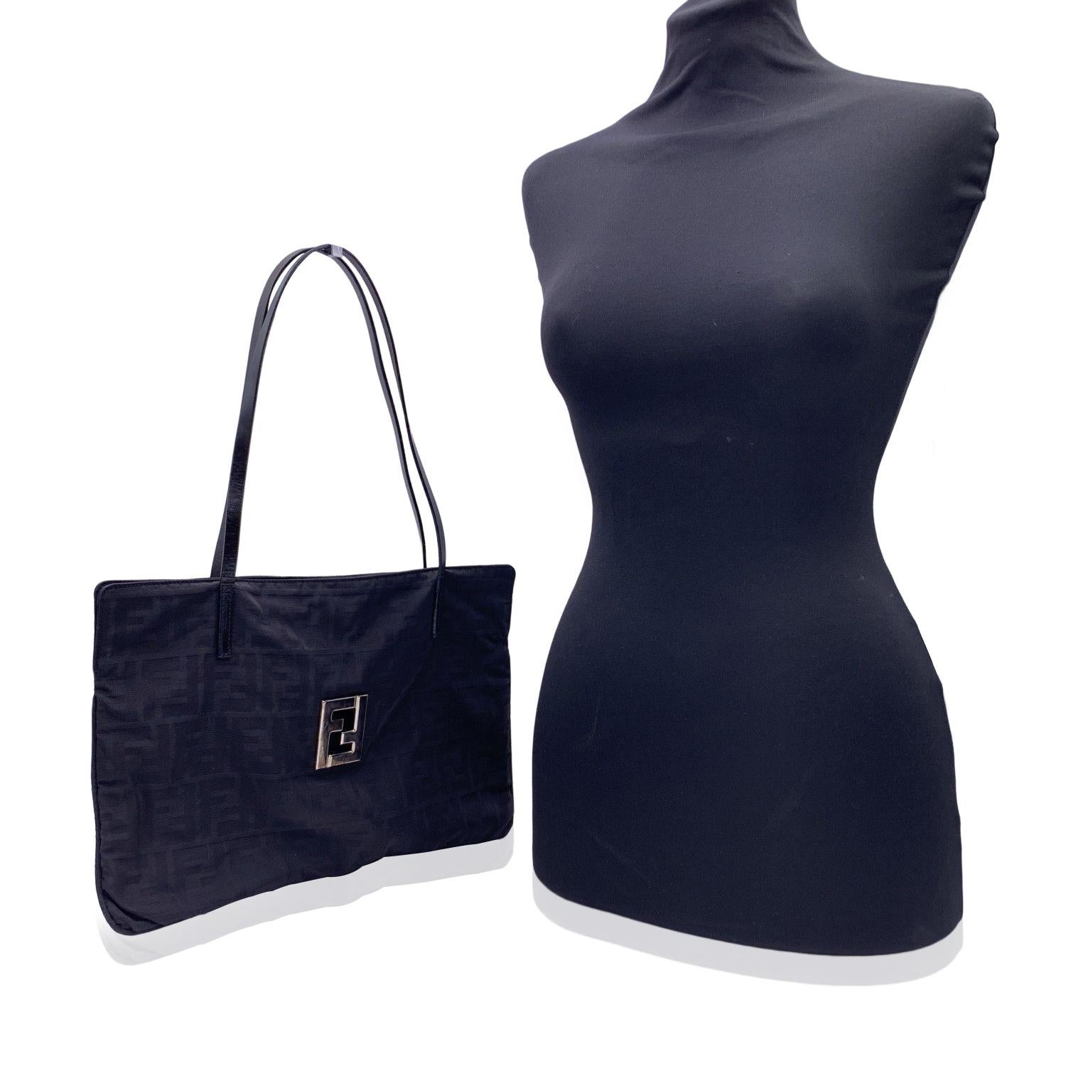 Fendi tote bag crafted in black monogram canvas with black genuine leather shoulder straps. Cut-out FF - FENDI logo on the front. Magnetic button closure on top. Black canvas lining. 1 side zip pocket inside. 'Fendi - Made in Italy' tag inside.