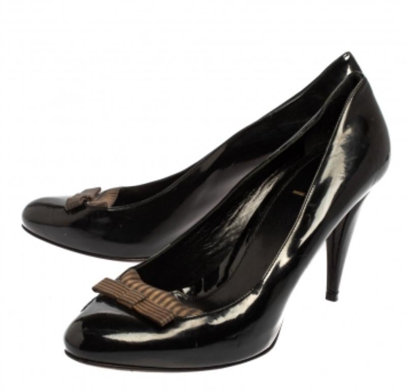 Every wardrobe deserves a classic pair of pumps and what better than these splendid ones from Fendi! The black pumps are crafted from patent leather and fabric and styled with delicate bows on the vamps. They come equipped with comfortable