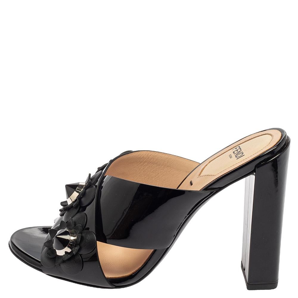 Beautifully designed, these mules from Fendi are truly charming! They are crafted from back patent leather and styled with an open toe silhouette. They exhibit floral applique detailed cross straps on the vamps and come endowed with comfortable