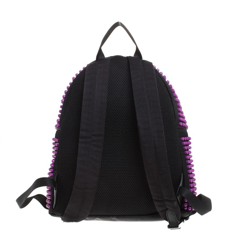 The stylish Fendi backpack comes with the iconic Karl design. The trendy bag in black and purple is crafted with nylon and designed incredibly with studs all over the front and sides. A front zip pocket, a main fabric interior and adjustable