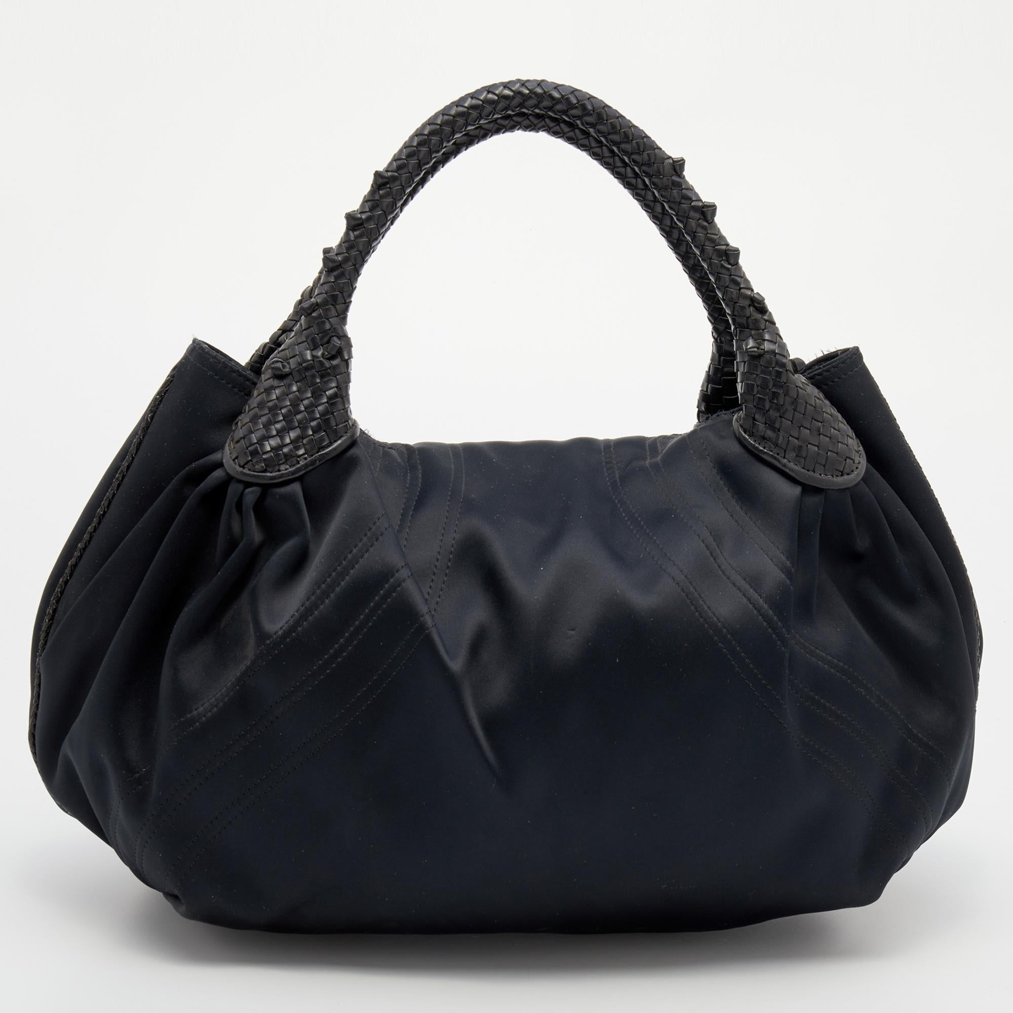 This uber-chic Spy hobo is from Fendi. It is made from black satin with leather trims and features two leather handles having a weave pattern. The front flap opens to a fabric interior that can easily fit your daily essentials. Flaunt this beauty