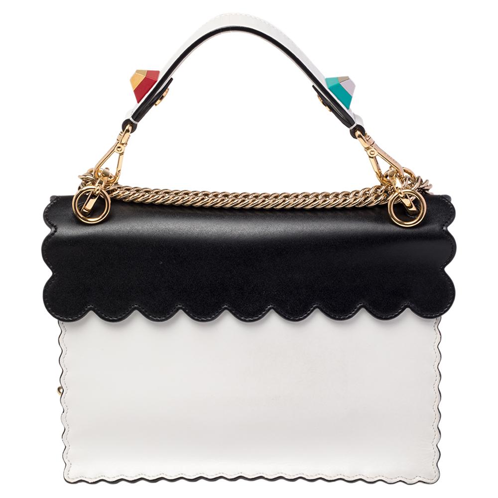 This Kan I F Fendi bag exudes an aura of excellence and an unequaled standard of craftsmanship. It has been crafted from leather in shades of white & black and styled with pyramid studs and scalloped edges. It opens to a spacious suede-lined