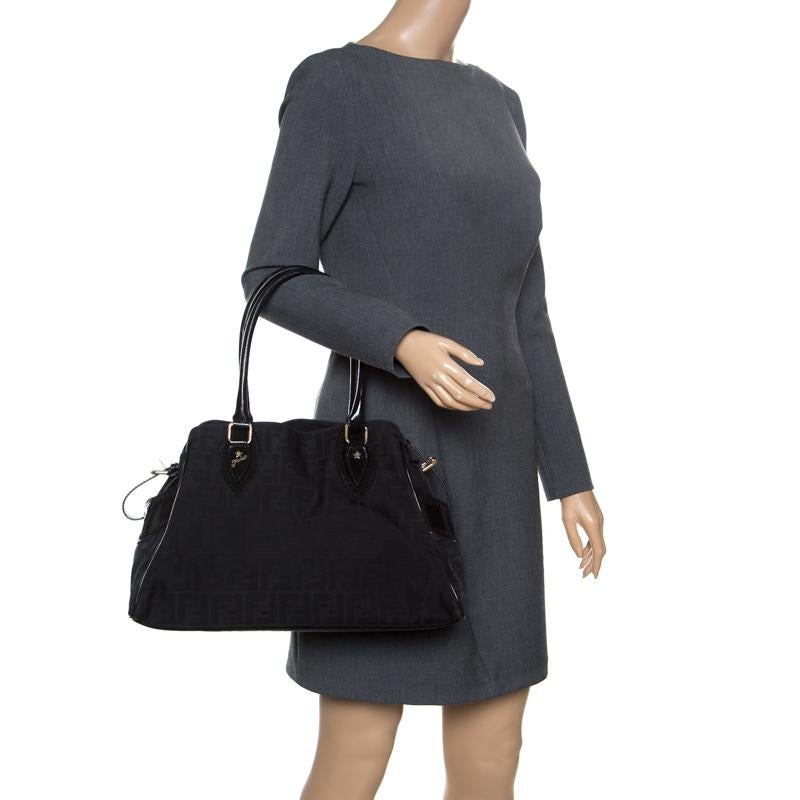 This Fendi Du Jour tote is perfect for everyday use. Crafted with signature Zucca fabric along with leather trims and belt details to the side, this carryall has a classic black hue and dual top handles for easy carriage. Its fabric lined interior