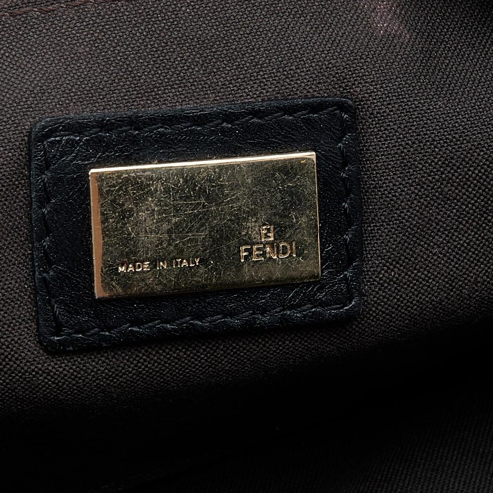 This shoulder bag from the House of Fendi exemplifies luxury and elegance in every way! This creation is made from black Zucchino canvas and leather, with a gold-tone logo accent placed on the front. It has a front pocket, a single handle, and a