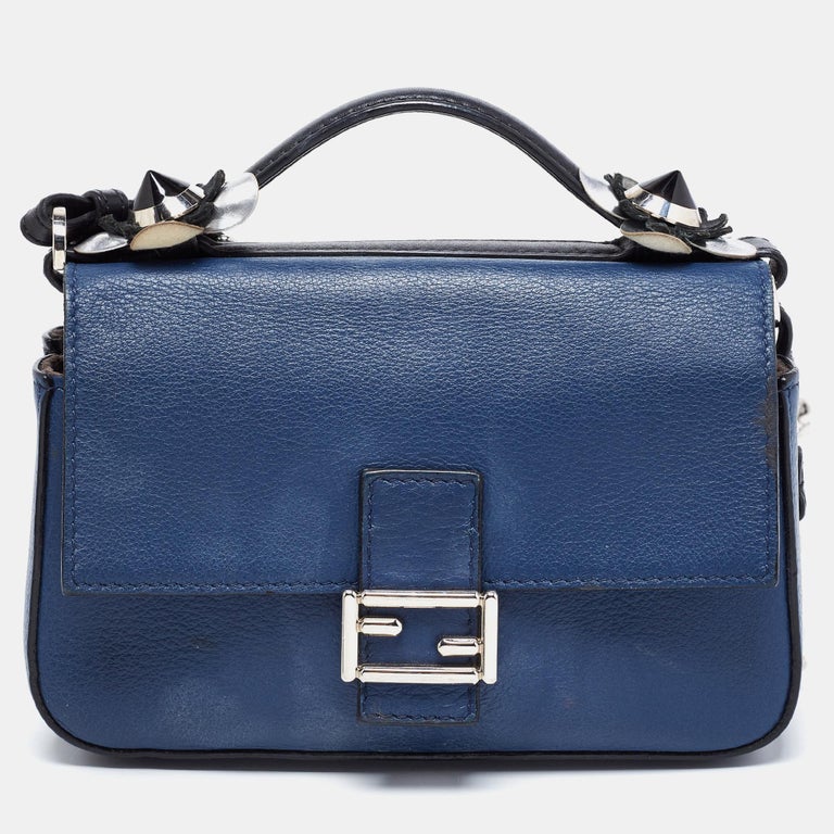 This Fendi micro baguette bag is truly lovely in its design. It is meticulously crafted from luxe leather and displays floral embellishments on the front flap and the top handle. Carry the blue-black bag for your dinner outings!

Includes: Original