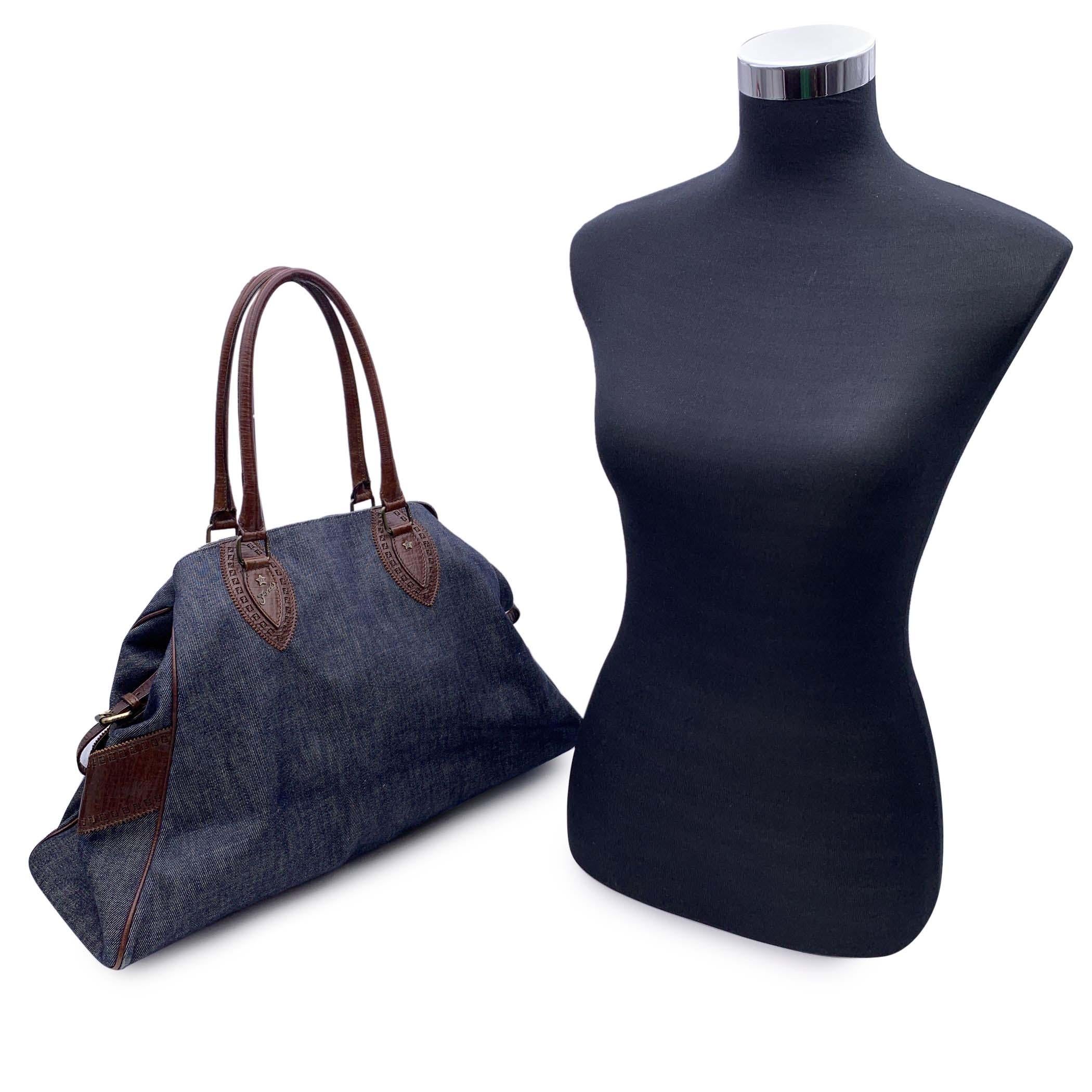Stylish 'Bag Du Jour' by Fendi. Crafted from blue denim with brown leather trim and handles.It features two side pockets with buckle closure. Rolled leather handles, double button closure on top + security clasp closure. FENDI cutout monogram on