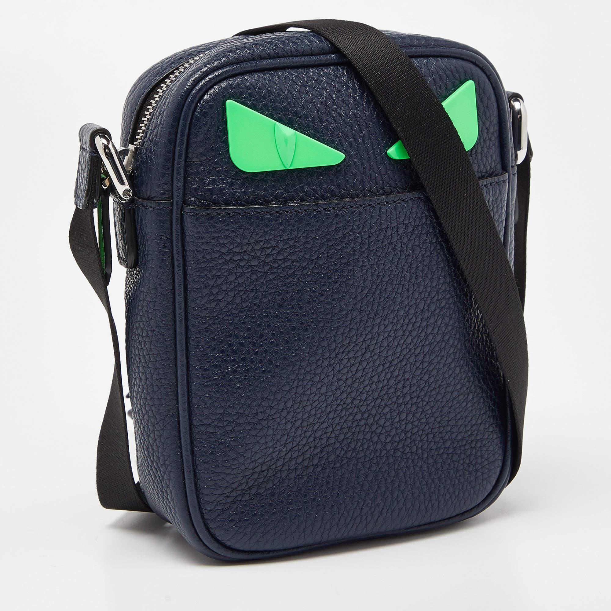 Die Tasche von Fendi ist ein stilvolles und verspieltes Accessoire. Sie ist aus luxuriösem blauem Leder gefertigt und zeigt das ikonische Monsteraugen-Design von Fendi mit Details in leuchtenden Farbtönen. Das kompakte Crossbody-Design macht sie