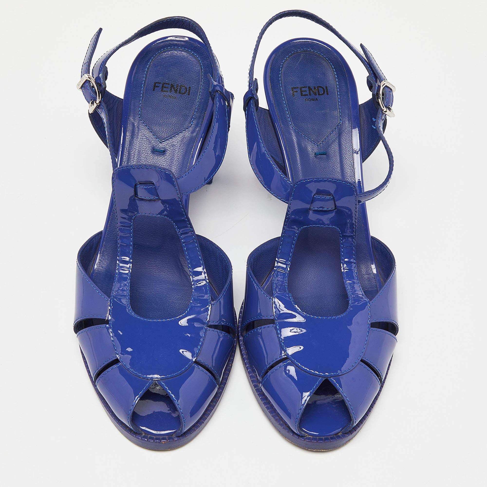 Stylish cut-out details and a striking blue hue define these Fendi sandals. Made from patent leather, they are secured with an ankle buckle closure and are stacked upon block heels.

Includes: Original Dustbag

