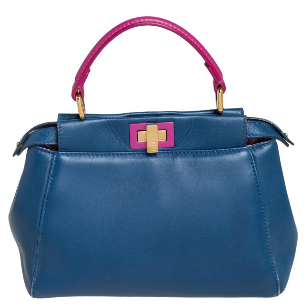 This exquisite Peekaboo from Fendi is highly coveted, and since its birth in 2009, it has swayed us with its shape, design, and beauty. This version comes meticulously crafted from blue leather and is designed with a pink top handle for you to swing
