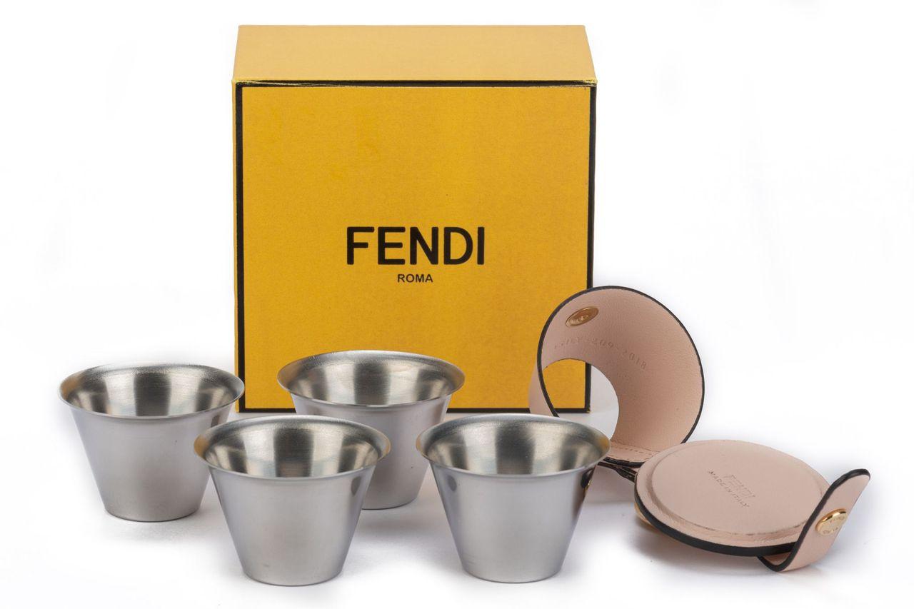 Fendi shot holder in powder pink with gold hardware including 4 steel shot glasses. The piece can be used as a key ring. The item is new and comes with a box.