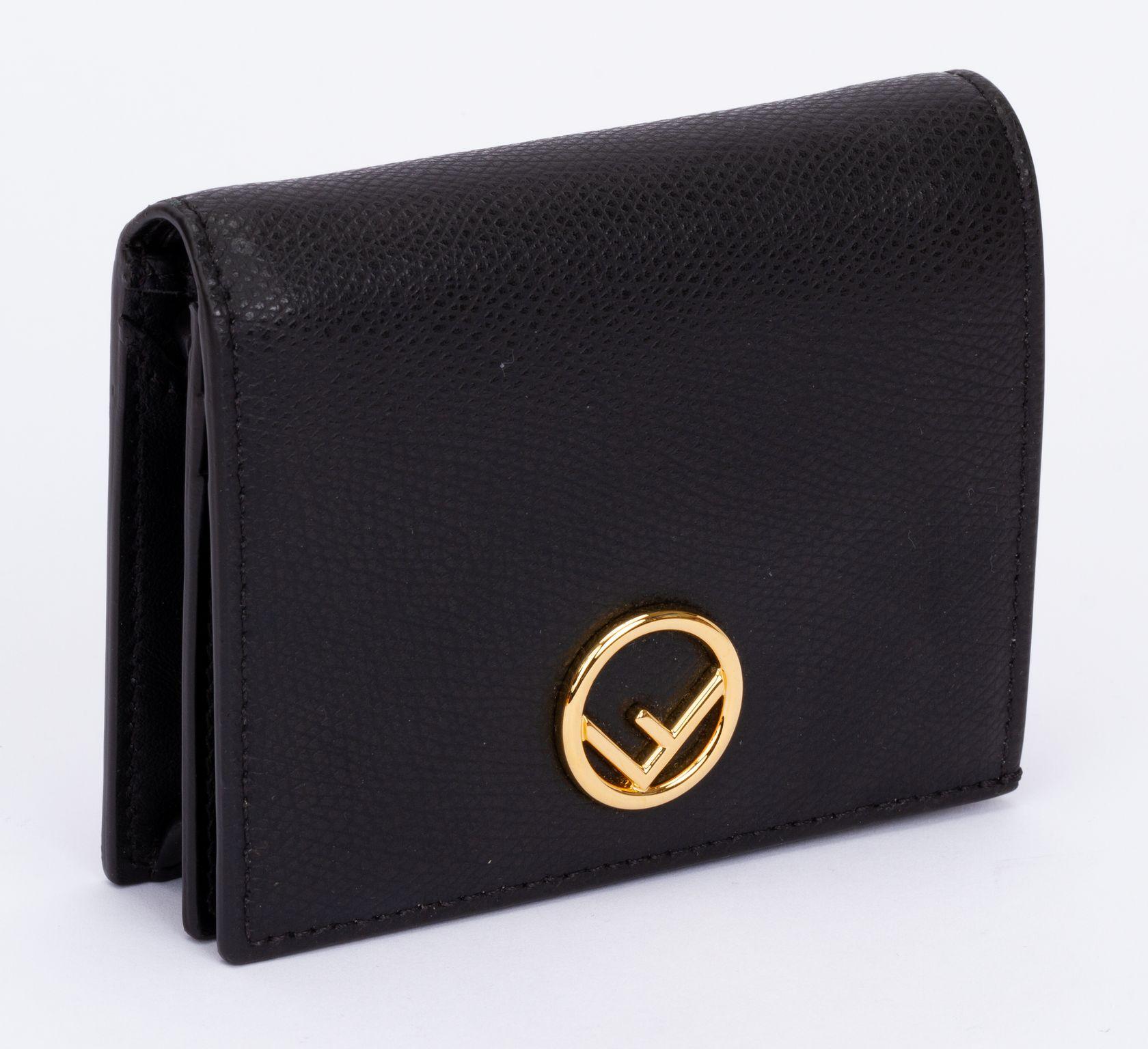 Fendi wallet made of leather in black. The wallet has several compartments for money and cards. On the front the clasp is a circle in the center is an F. The wallet is brand new and comes with the tag, original box and dust cover.