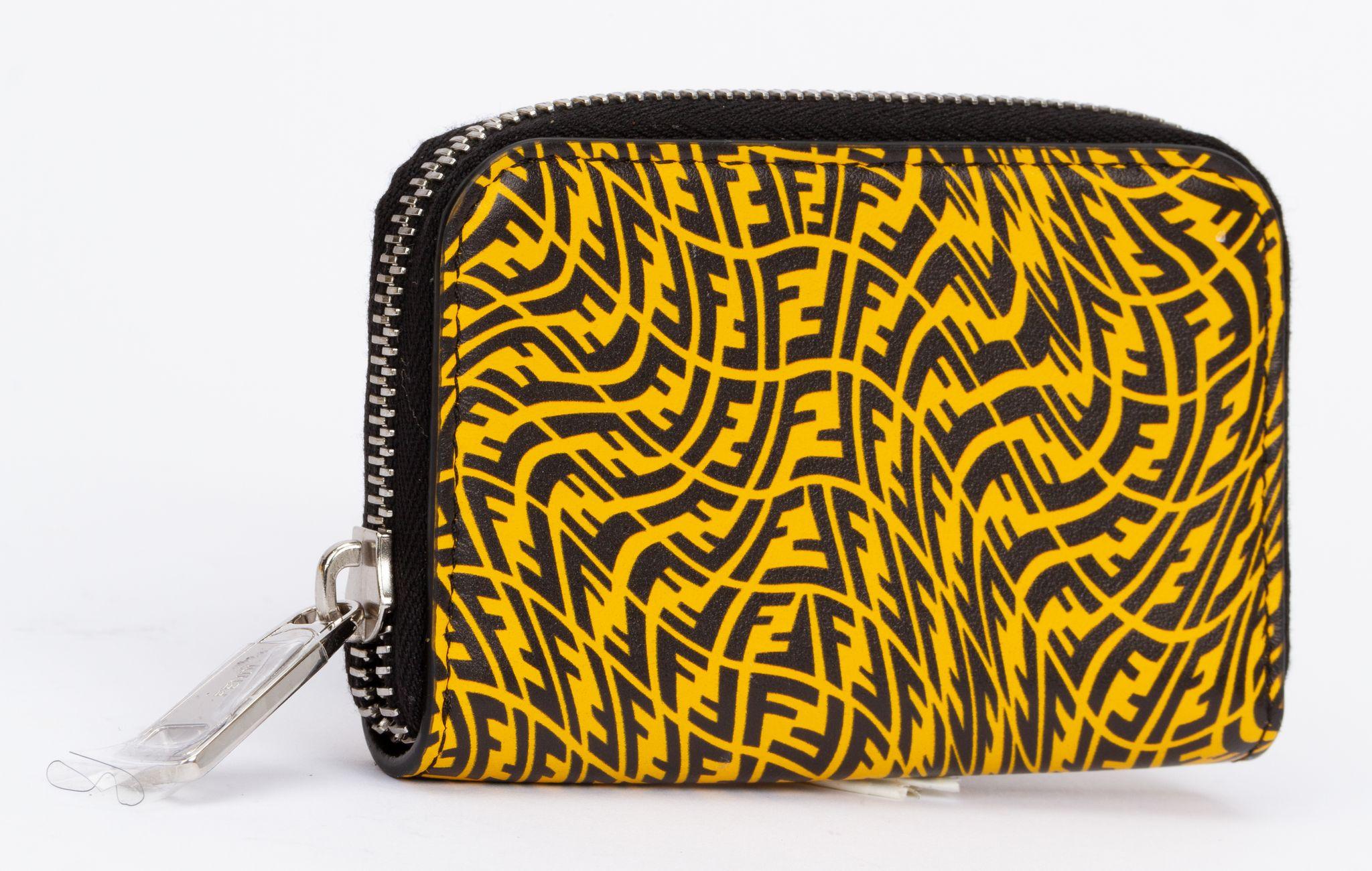Fendi wallet made of leather in a bright yellow. The vertigo print is made of many F logos which are swirled around. The inside is black and has some card holders as well as an department for money. The piece is new and comes with a tag, original