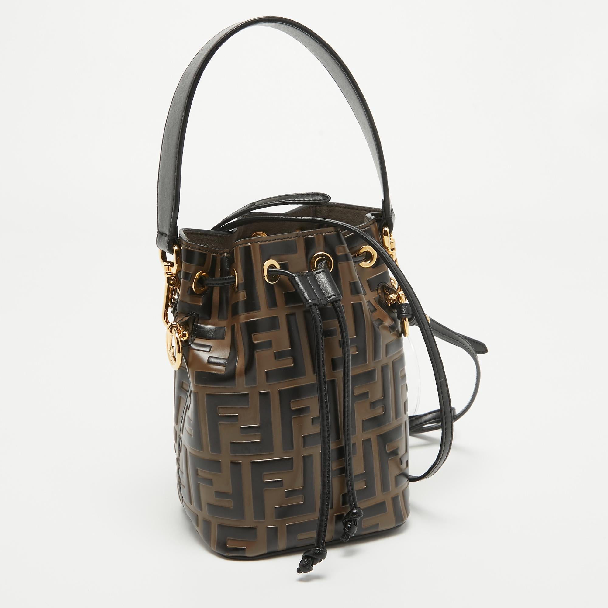 From the House of Fendi, this mini Mon Tresor bucket bag will offer you a luxe design and ease. It is made from brown-black Zucca leather on the exterior and comes with gold-toned hardware, a drawstring detail, and a single top handle. This bag is