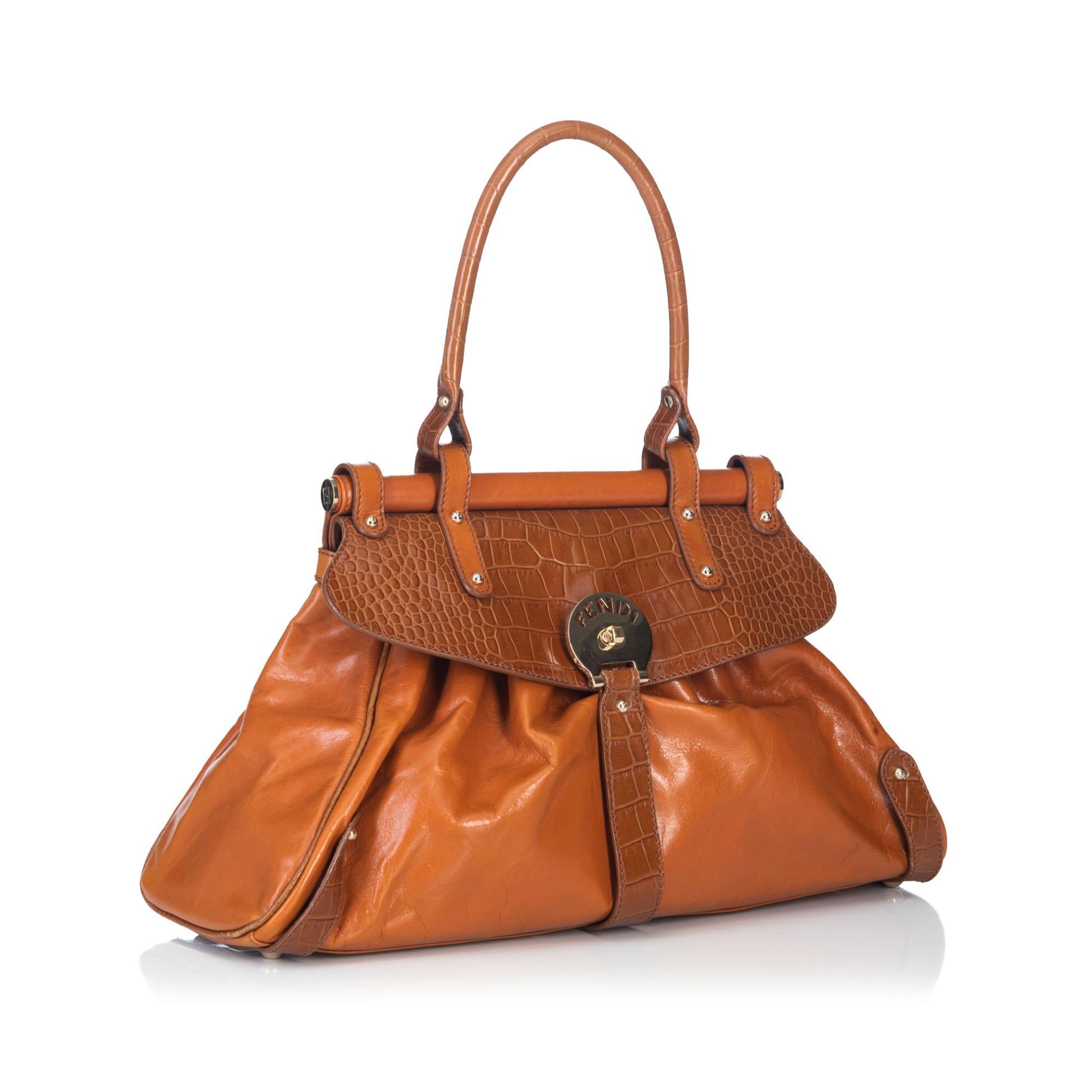 The Magic Bag features a leather body with embossed crocodile trim, single rolled leather handle, front flap with twist-lock closure, and an interior zip pocket. It carries as AB condition rating.

Inclusions: 
This item does not come with