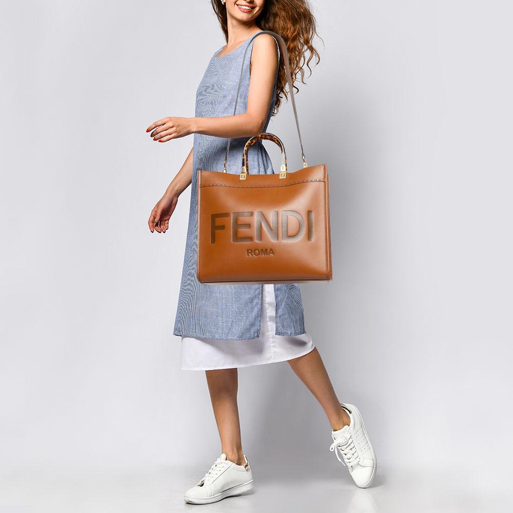 The Fendi Sunshine Tote is a luxurious and versatile handbag. Crafted from supple brown leather, it features a spacious interior. The iconic Fendi logo is subtly embossed, and the bag is adorned with elegant gold-tone hardware. A detachable shoulder