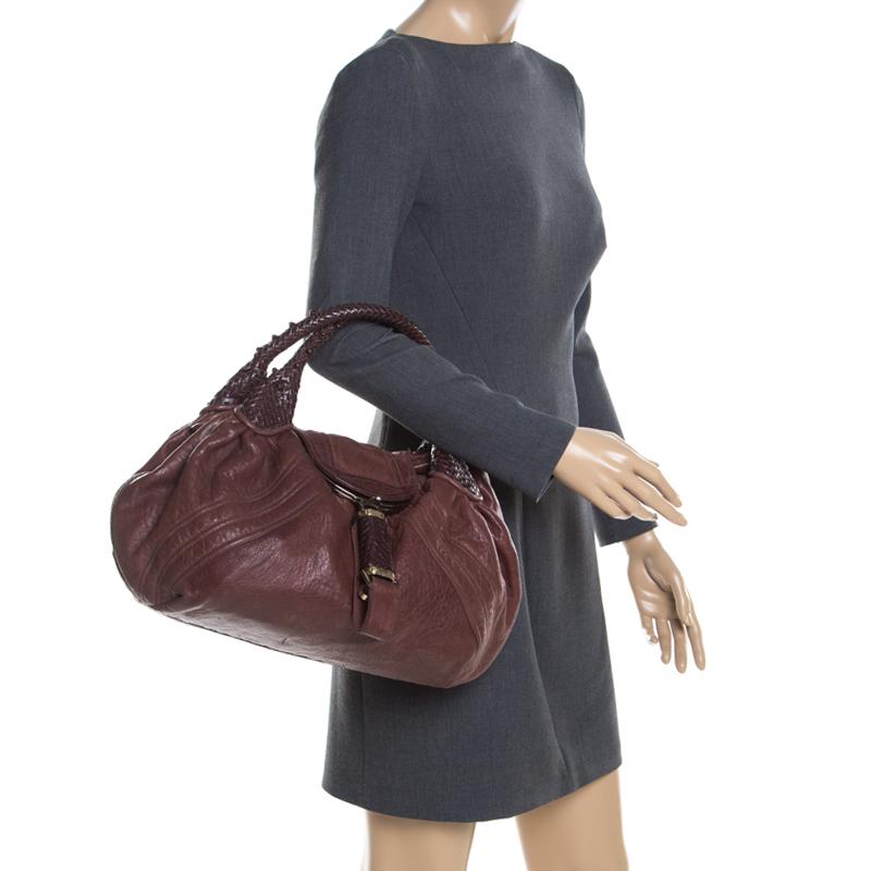 The Spy is an iconic style from Fendi, designed by Silvia Venturini Fendi and released in 2005. This gorgeous bag is crafted with pebbled leather features a subtle brown hue. It comes with several distinctive features that make it one-of-a-kind. Its
