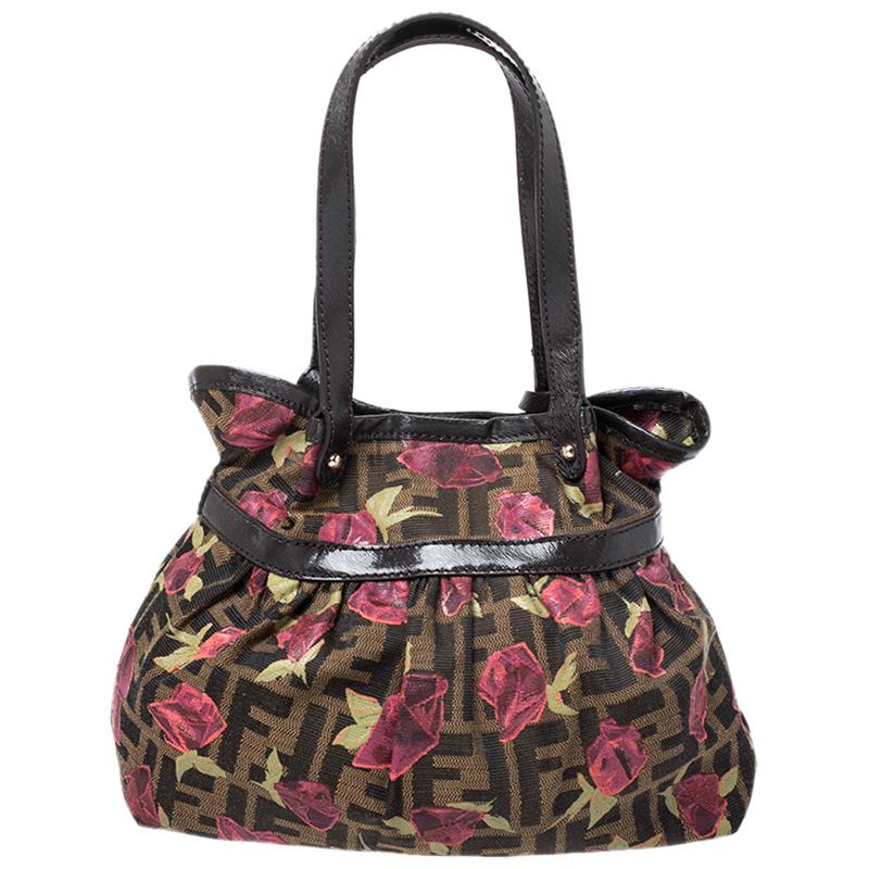 Get this fun creation from Fendi. Crafted from the brand's Zucca canvas and leather, it comes in a lovely shade of brown. The bag features a feminine pink rose print and is held by dual handles. It is equipped with a fabric interior, bag charm with
