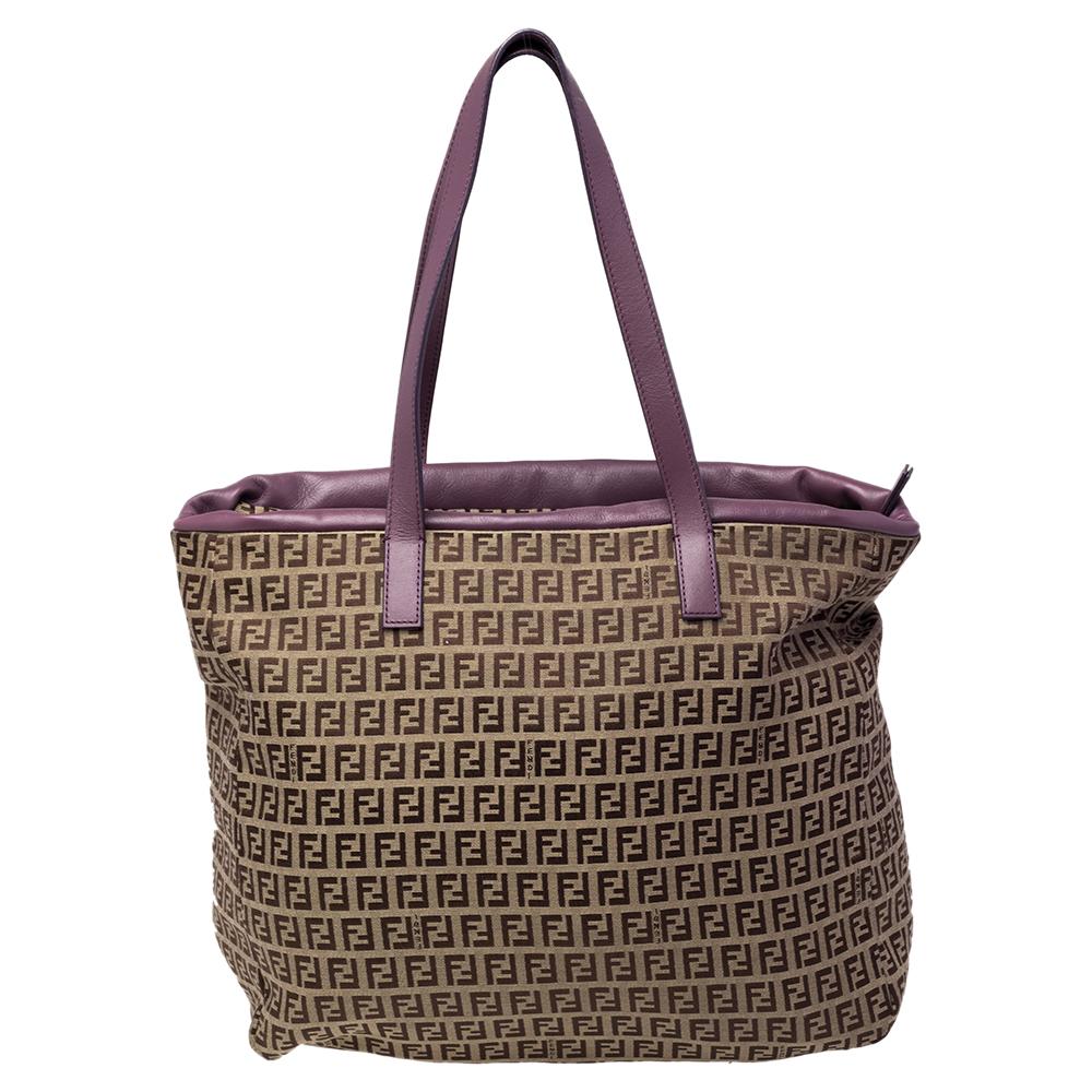 This elegant tote from Fendi is ideal for everyday use. Crafted from Zucchino canvas & leather, the brown & purple bag is held by two handles and a drawstring pocket in the front. The top opens to a spacious interior that is perfectly sized to hold