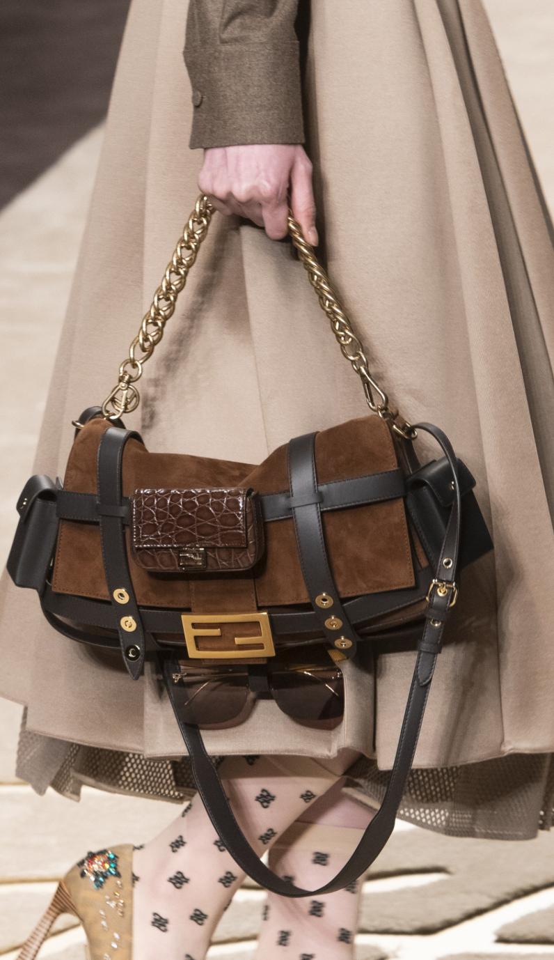 The Fendi Brown Suede Leather Trimmed Cage Baguette Shoulder Bag from circa 2019 epitomizes sophisticated luxury and versatile style. Crafted from rich brown suede, this handbag features a distinctive leather cage design that adds texture and depth.