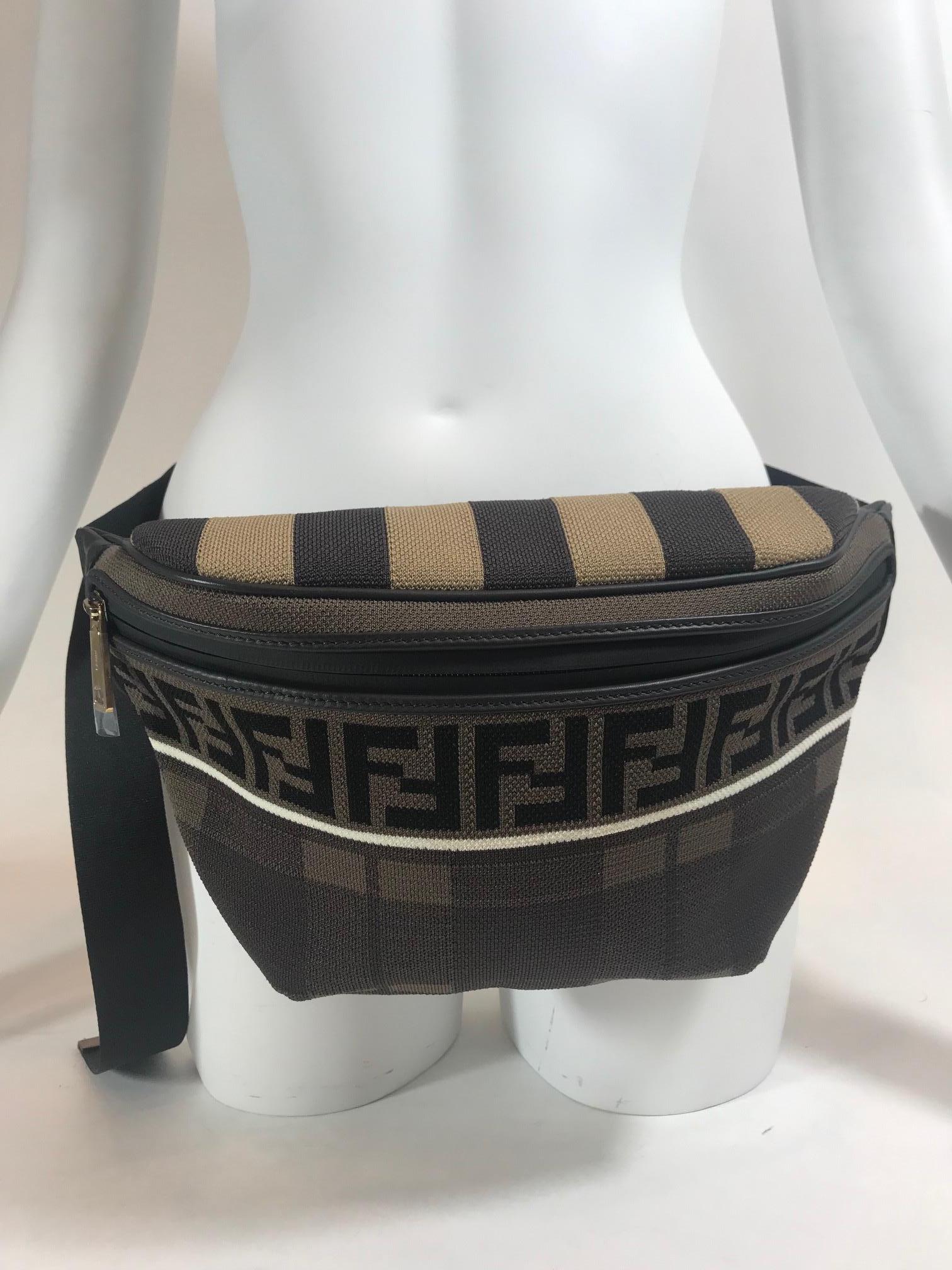 Brown tones with alternating tonal patterns and tonal calfskin trim throughout. Gold-tone hardware. Front zipper closure. Tonal stitching. Adjustable grosgrain belt-style strap featuring logo-engraved press-release fastening. Logo pattern knit in