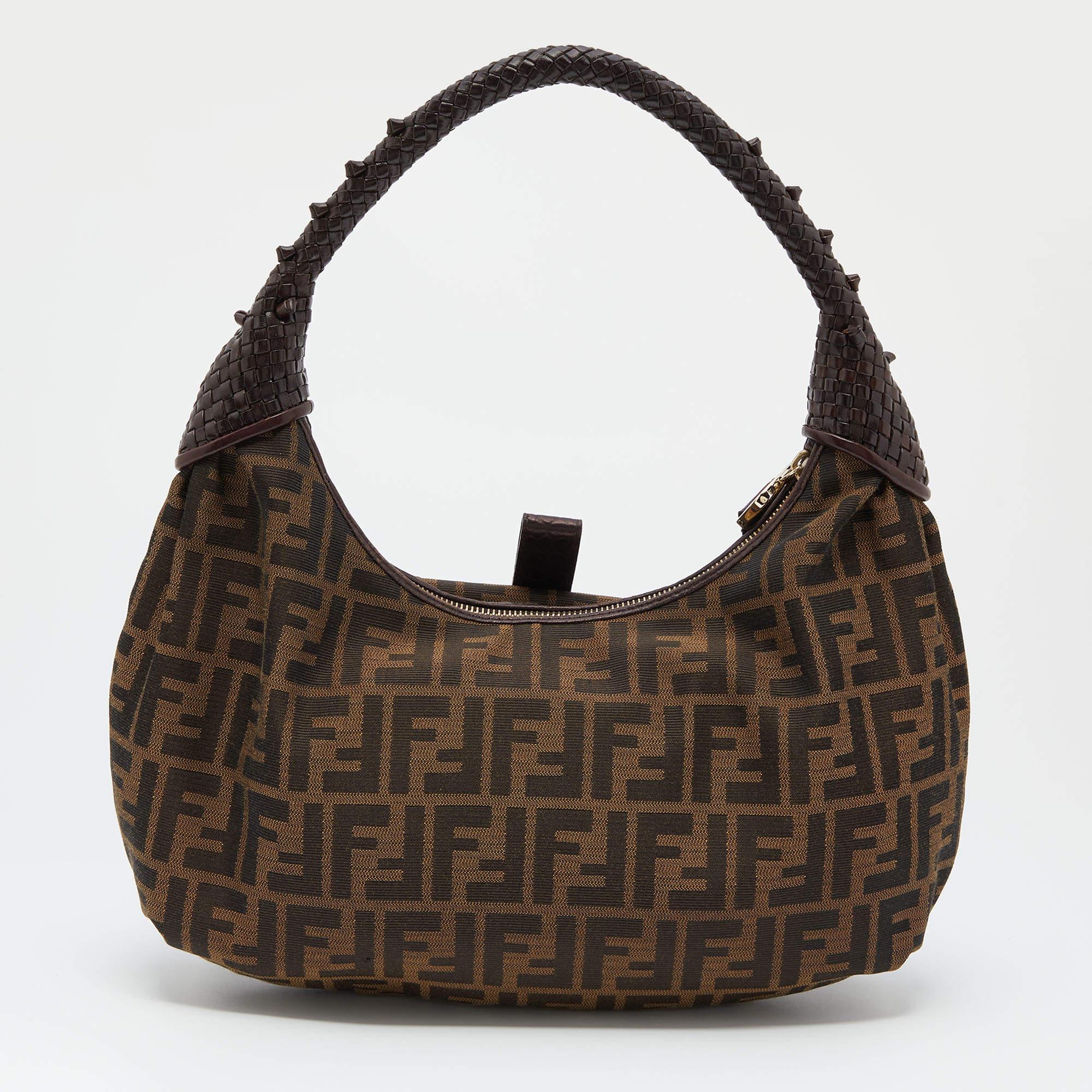 This chic Spy hobo is from Fendi. Crafted from classic Zucca canvas and styled with leather trims, it features a weave pattern on the handle. The zip top closure opens to a fabric lined spacious interior that will hold all your daily essentials.