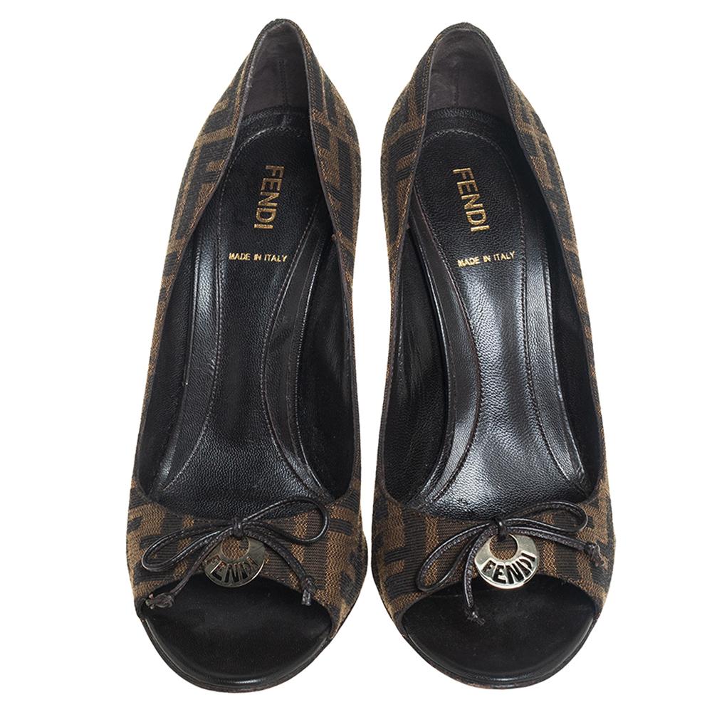 Trust Fendi to make you look ultra-stylish with these pumps! They are crafted from the signature Zucca canvas and look resplendent. These Italian beauties flaunt leather trims, peep-toes with bows & logo details and come equipped with high