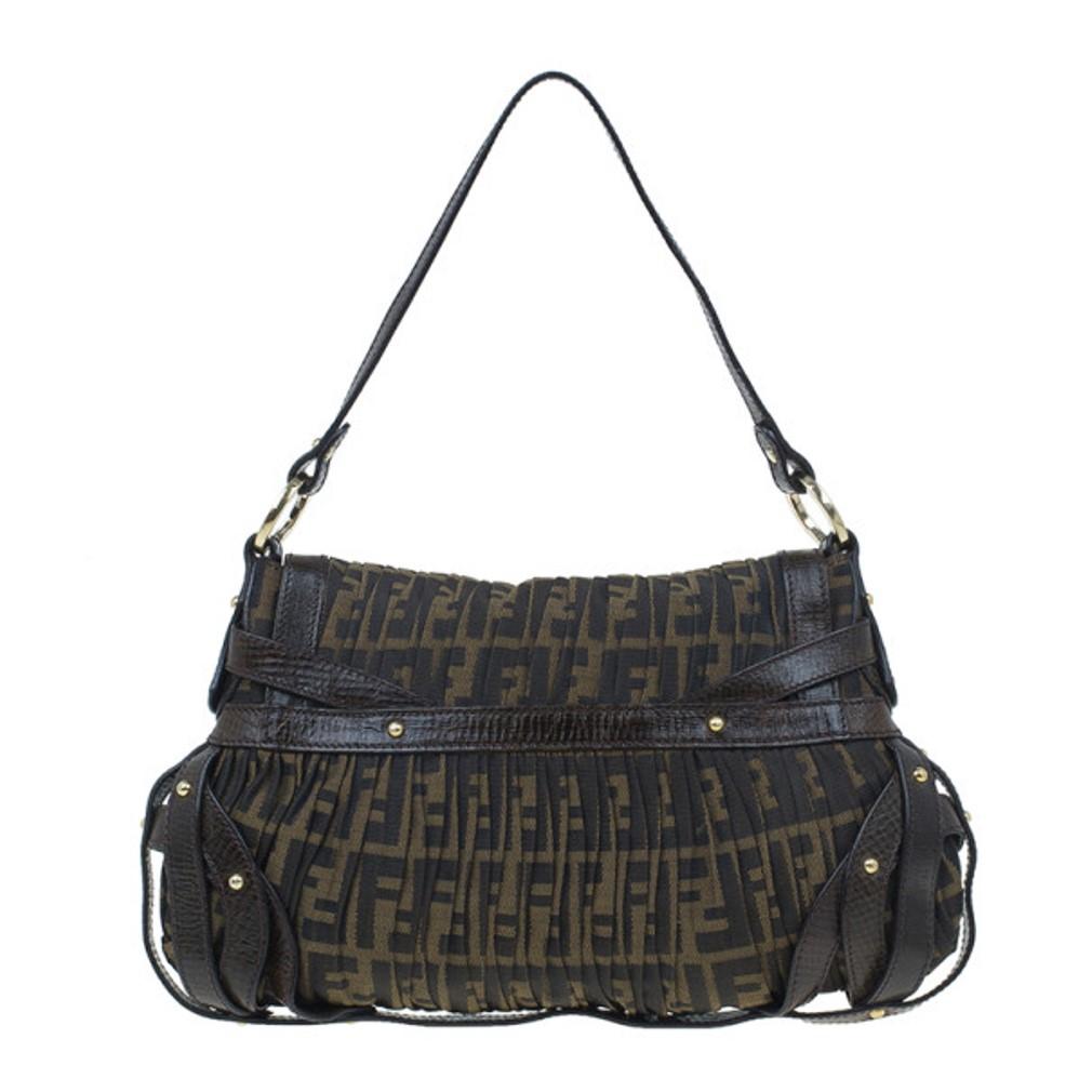 This gorgeous Fendi handbag features the signature Zucca print. Accented with brown studded leather trim, this bag has a single handle, gold-tone tings and a flap closure with a twist lock. The lined interior has one patch pocket.

